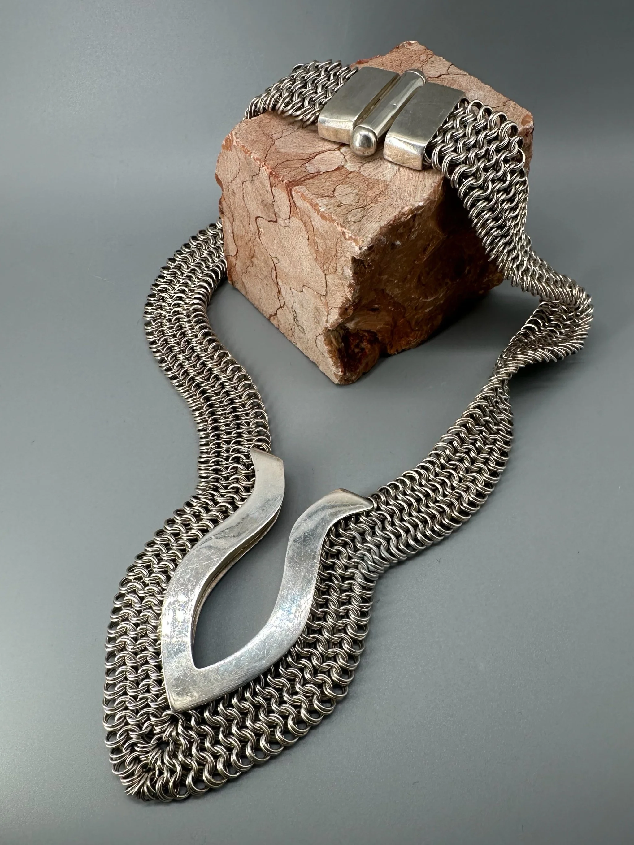 Piscis necklace by Ariadna Segafredo, crafted in woven metal mesh with a sculptural clasp for Crepundia Gioielli.