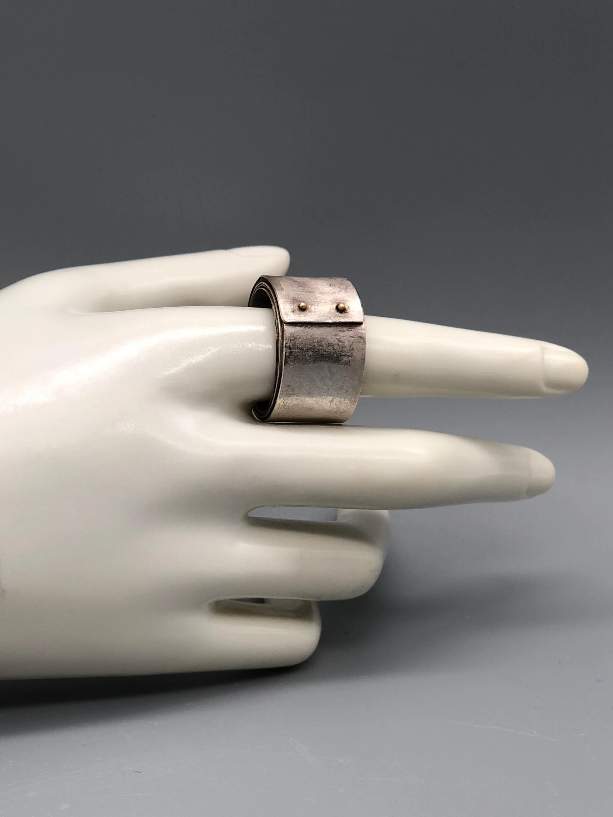 Girella ring by Mangàni in silver, featuring a wide coiled band accented with two small gold nails.