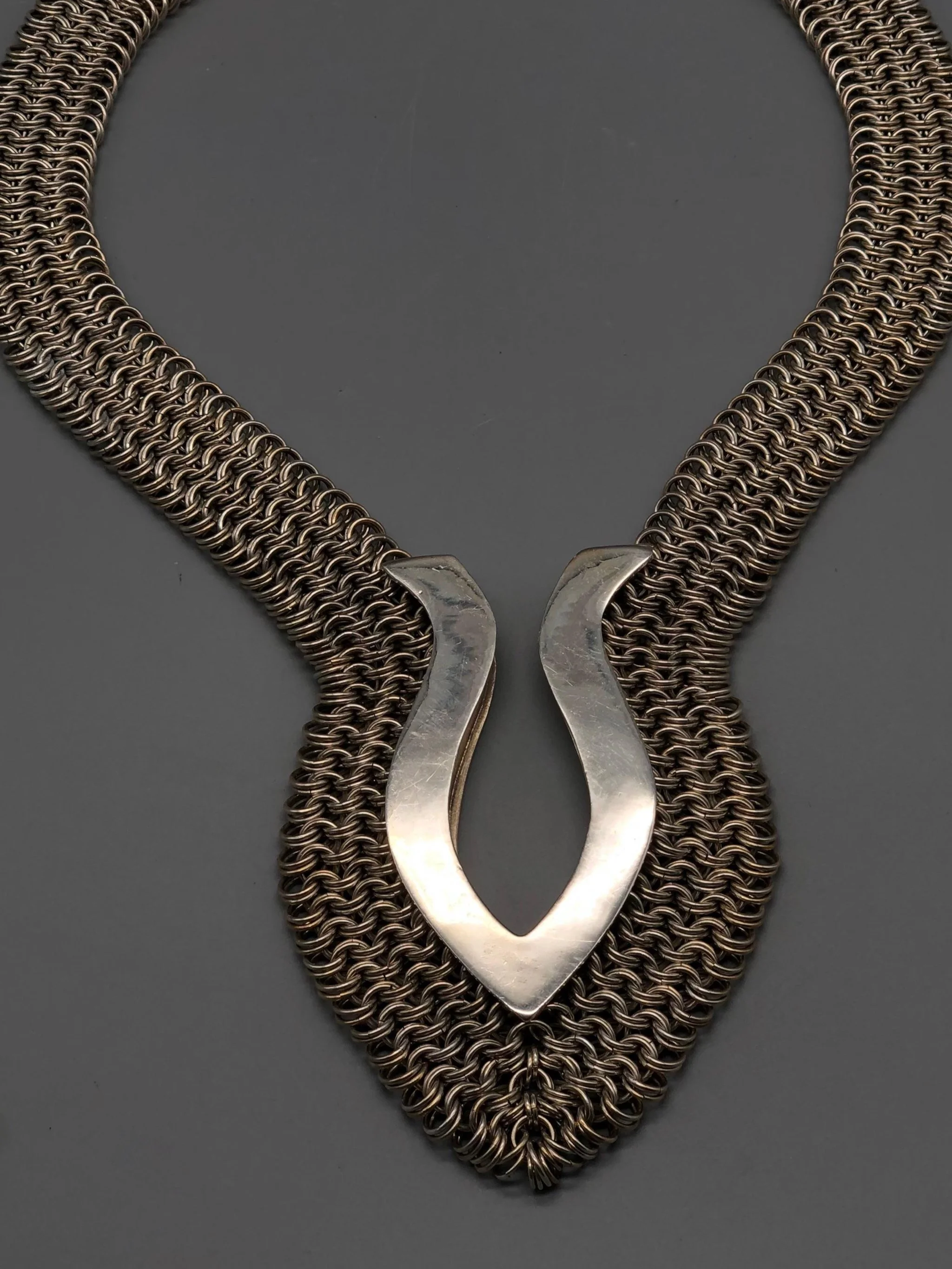 Piscis necklace by Ariadna Segafredo, crafted in woven metal mesh with a sculptural clasp for Crepundia Gioielli.
