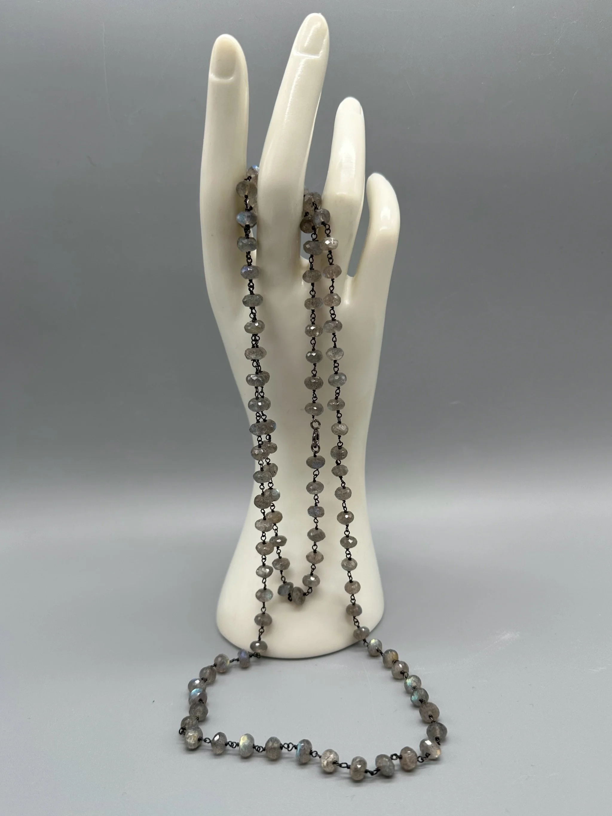Collana Bold Labradorite con pietre naturali grigie sfaccettate e riflessi iridescenti. Bold Labradorite necklace with faceted grey gemstones and iridescent reflections.