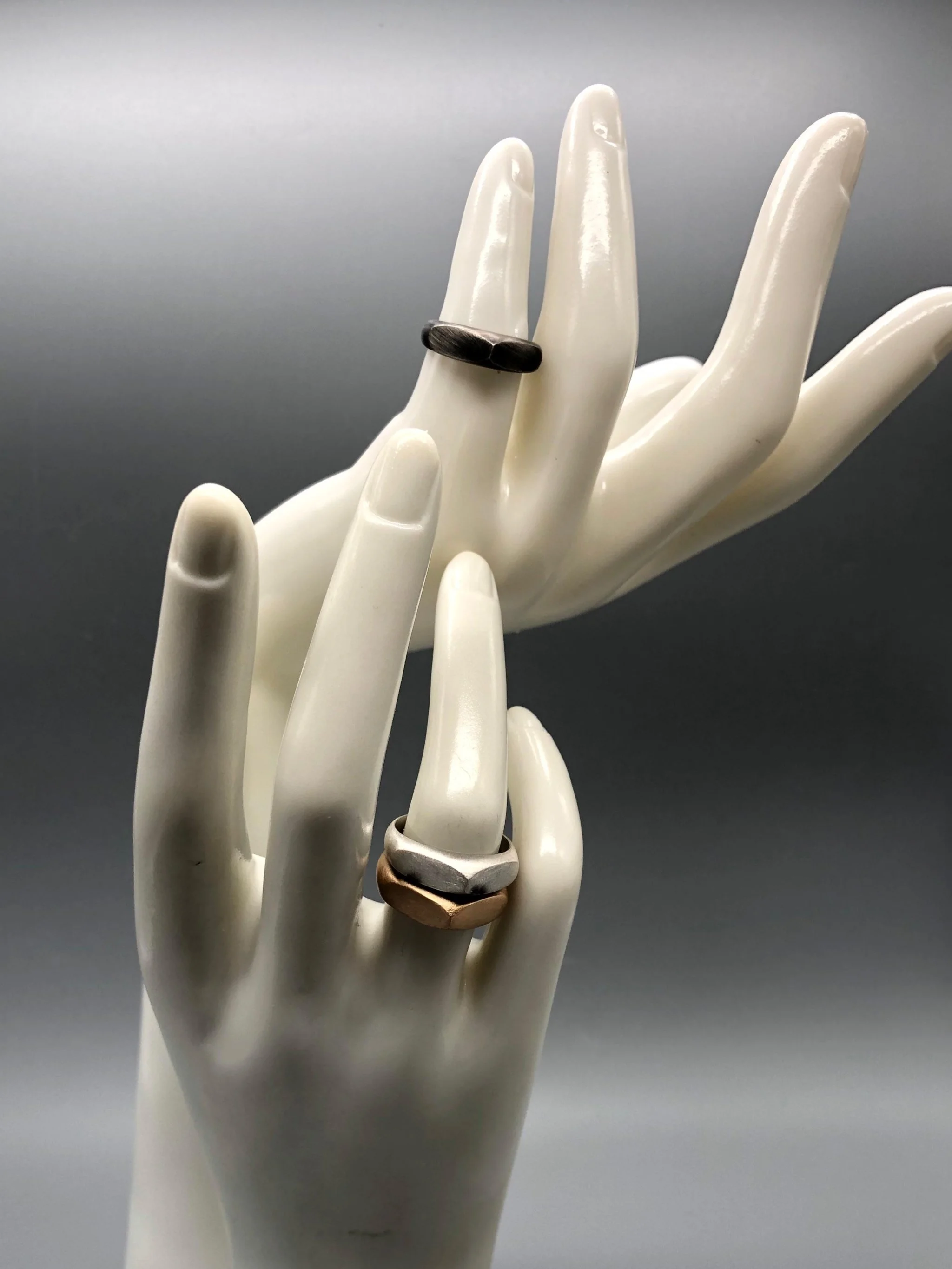 Tre anelli Cuspide di Crepundia Gioielli in argento, argento brunito e bronzo, sovrapposti in una composizione geometrica e scultorea.  Three Crepundia Cuspide rings in sterling silver, oxidized silve