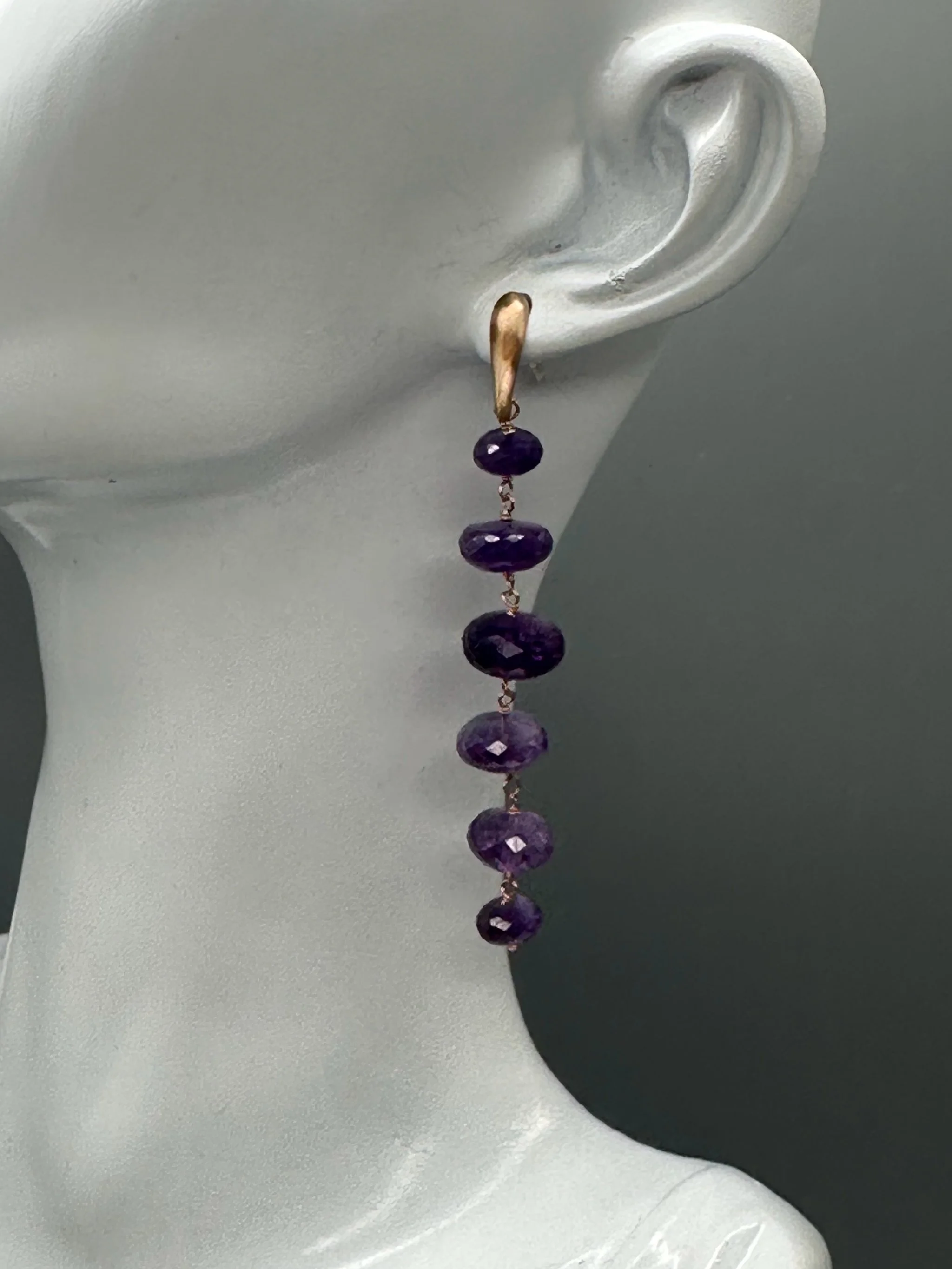 Orecchini Bold Ametista con pietre viola sfaccettate e montatura essenziale. Bold Amethyst earrings with faceted purple gemstones and a minimal metal setting.