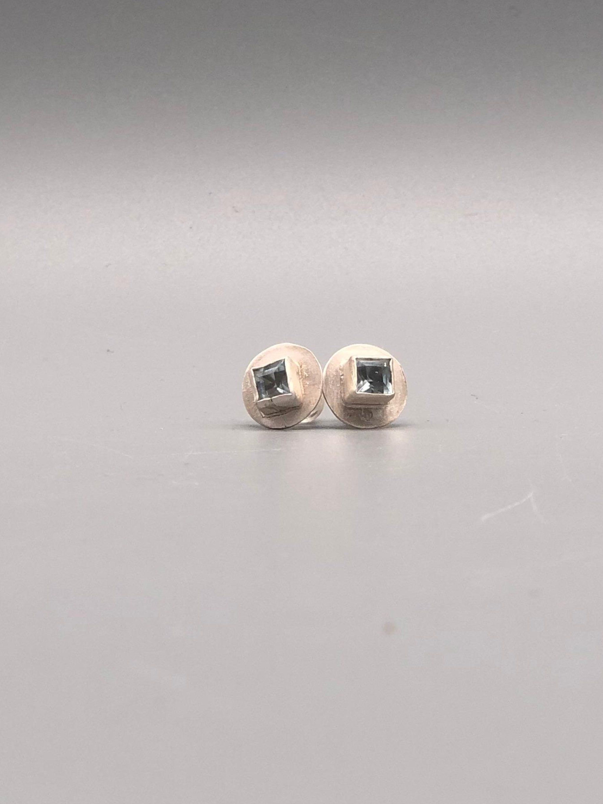 Monologue satin silver earrings with square aquamarine and raised geometric setting, Crepundia Gioielli Bologna.