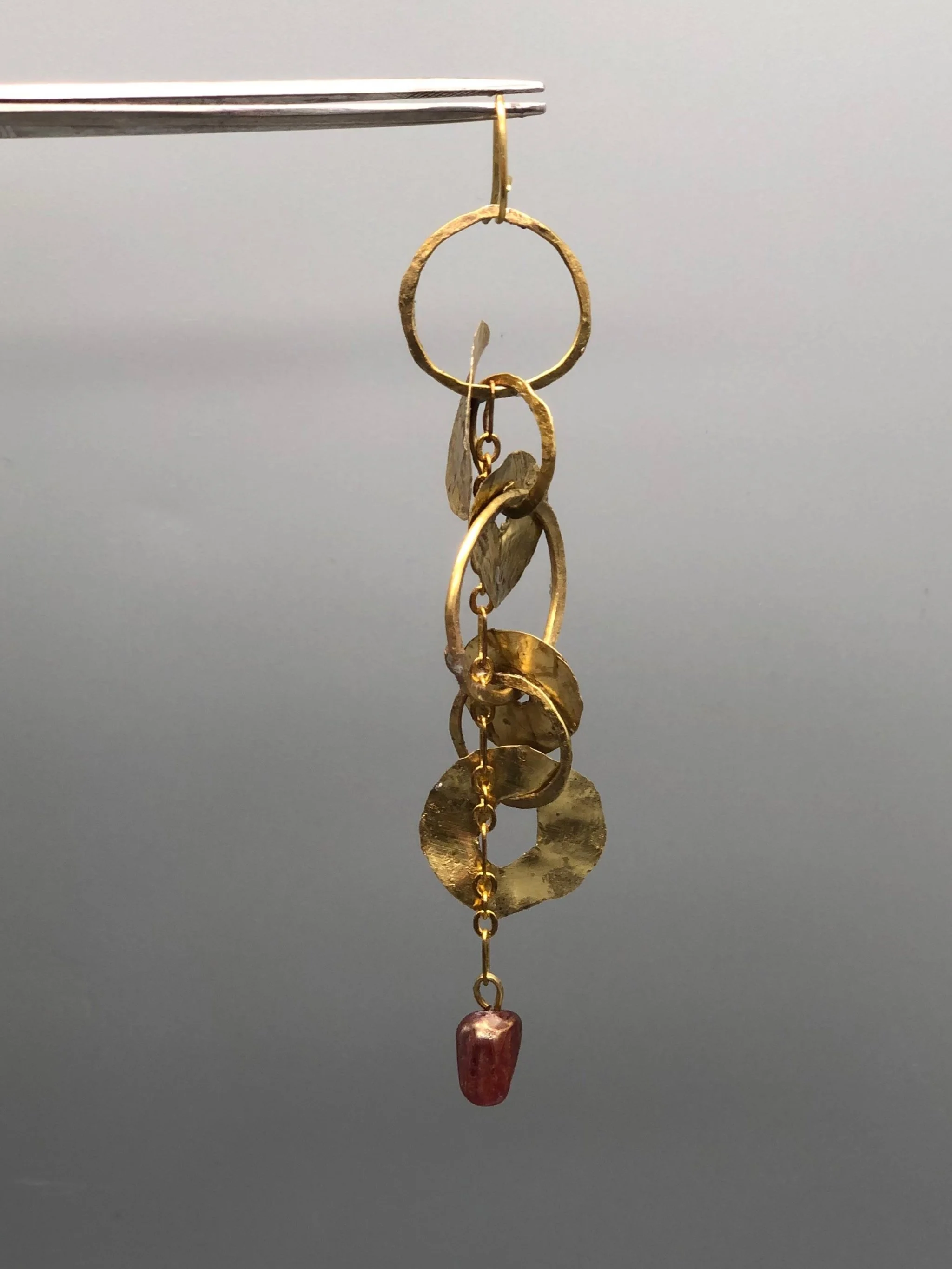 Mono orecchino Orbit Chain di Claudia Cuzzeri in ottone opaco con elementi circolari irregolari, catena e dettaglio in vetro di Murano