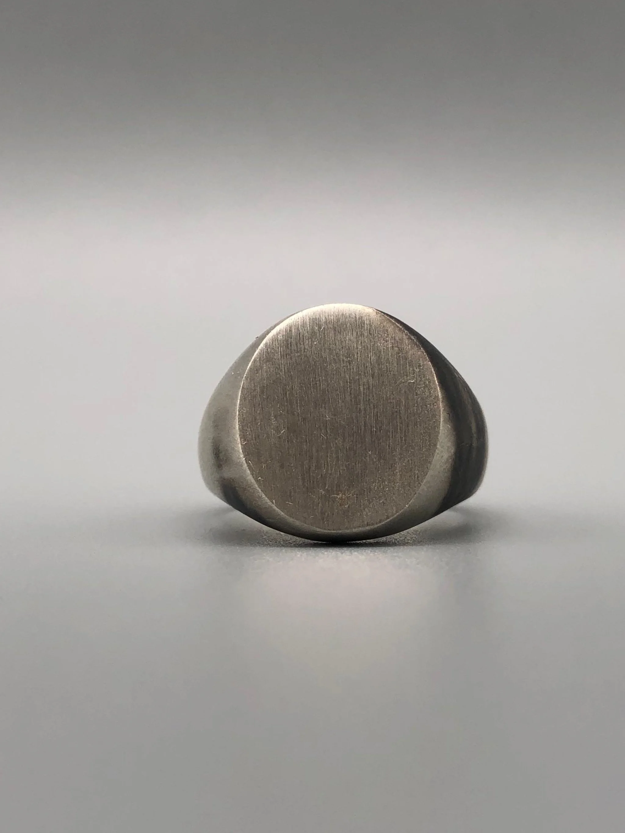 Anello Chevalière in argento opaco, gioiello contemporaneo dal volume pieno e dal design essenziale. Chevalière ring in matte silver, contemporary jewellery with a solid volume and essential design.