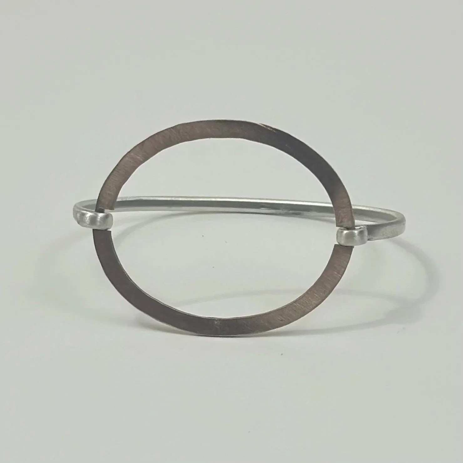 Bracciale rigido in bronzo e argento con elemento ovale centrale – Crepundia Gioielli