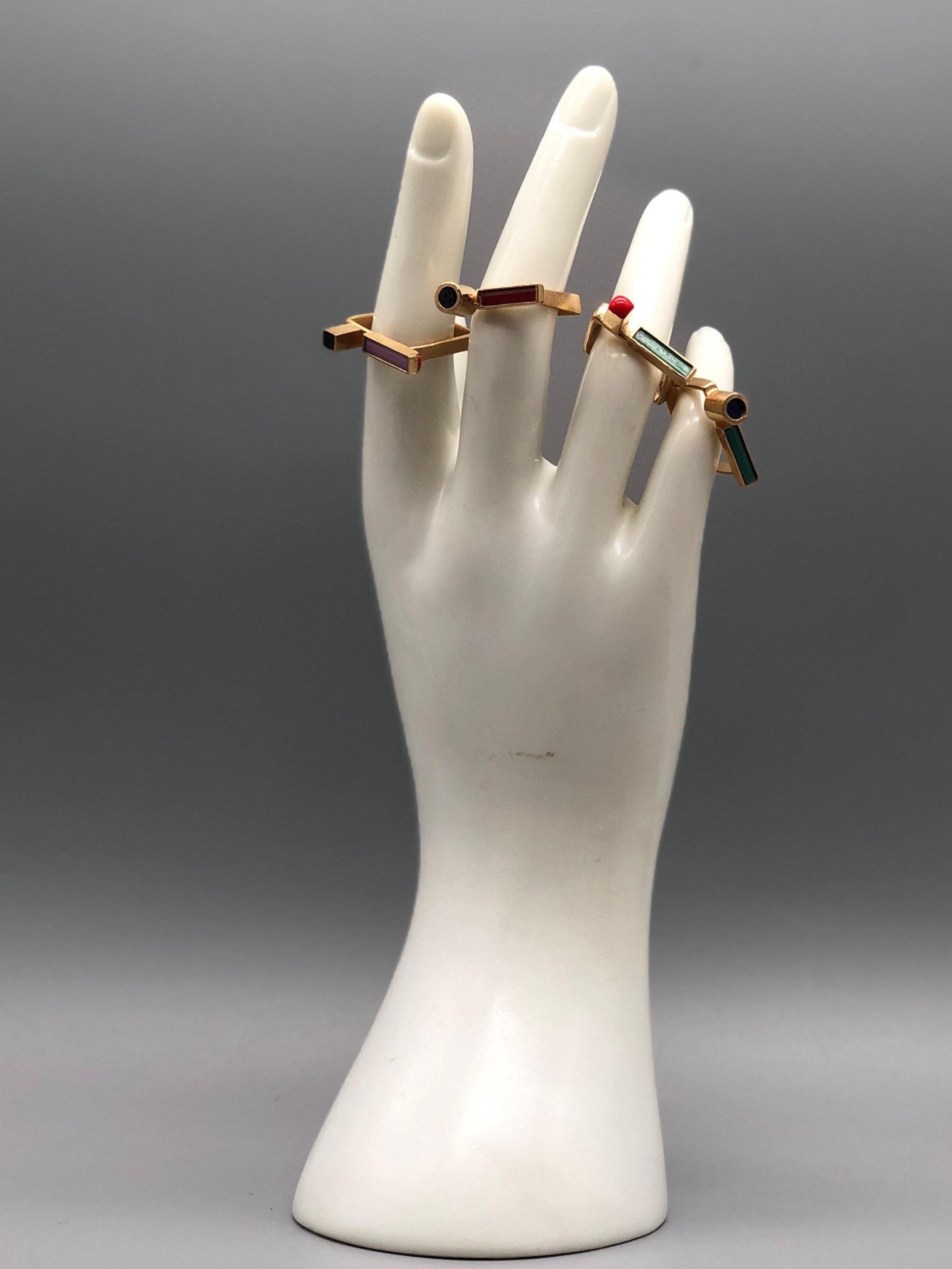 Contemporary rings by EL Gioielli for Crepundia Gioielli Bologna, geometric gold-toned rings with colored enamel details displayed on neutral background and worn on hand