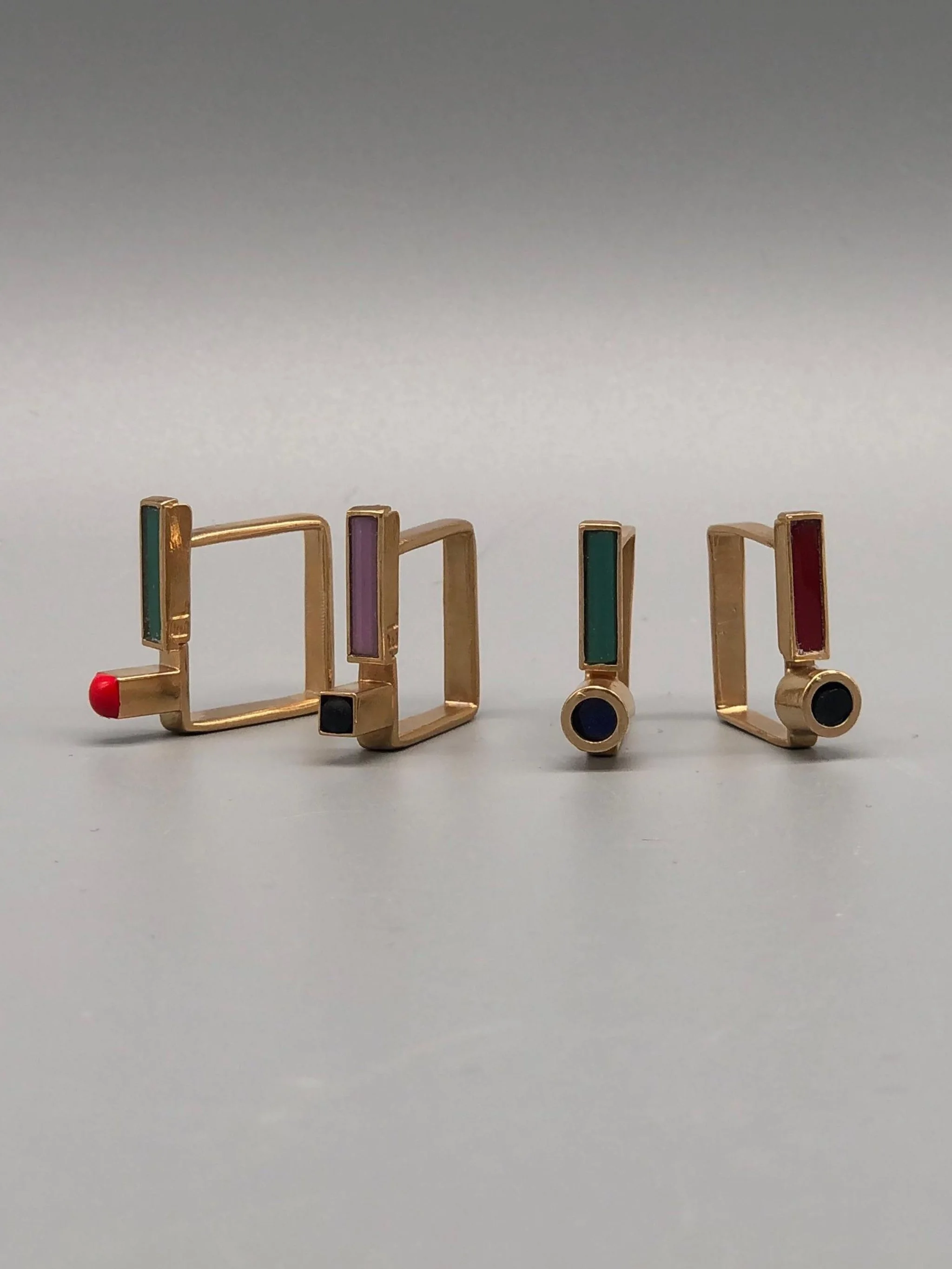 Contemporary rings by EL Gioielli for Crepundia Gioielli Bologna, geometric gold-toned rings with colored enamel details displayed on neutral background and worn on hand