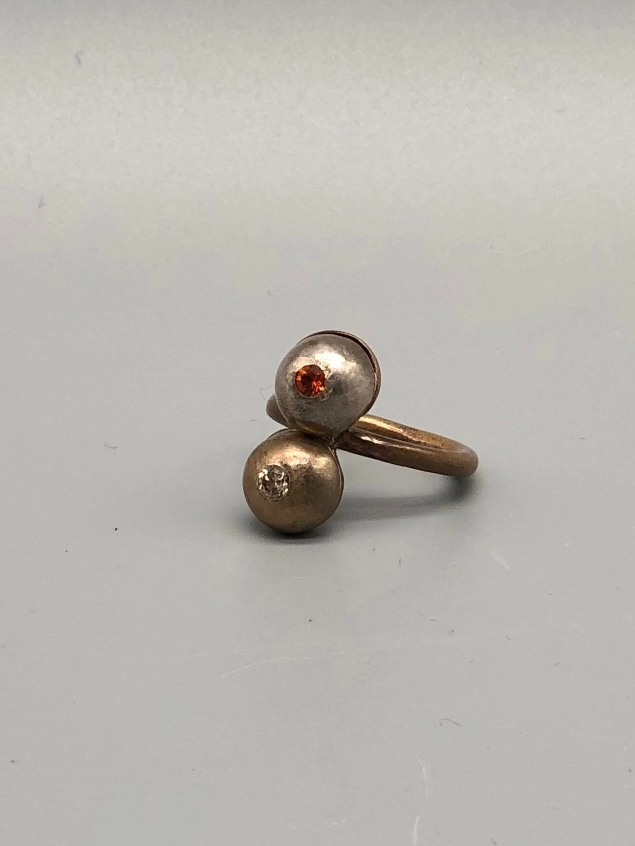 Riccardo Raimondi bronze ring with cognac quartz and spessartite garnet, double sphere design, contemporary jewelry Crepundia Gioielli Bologna