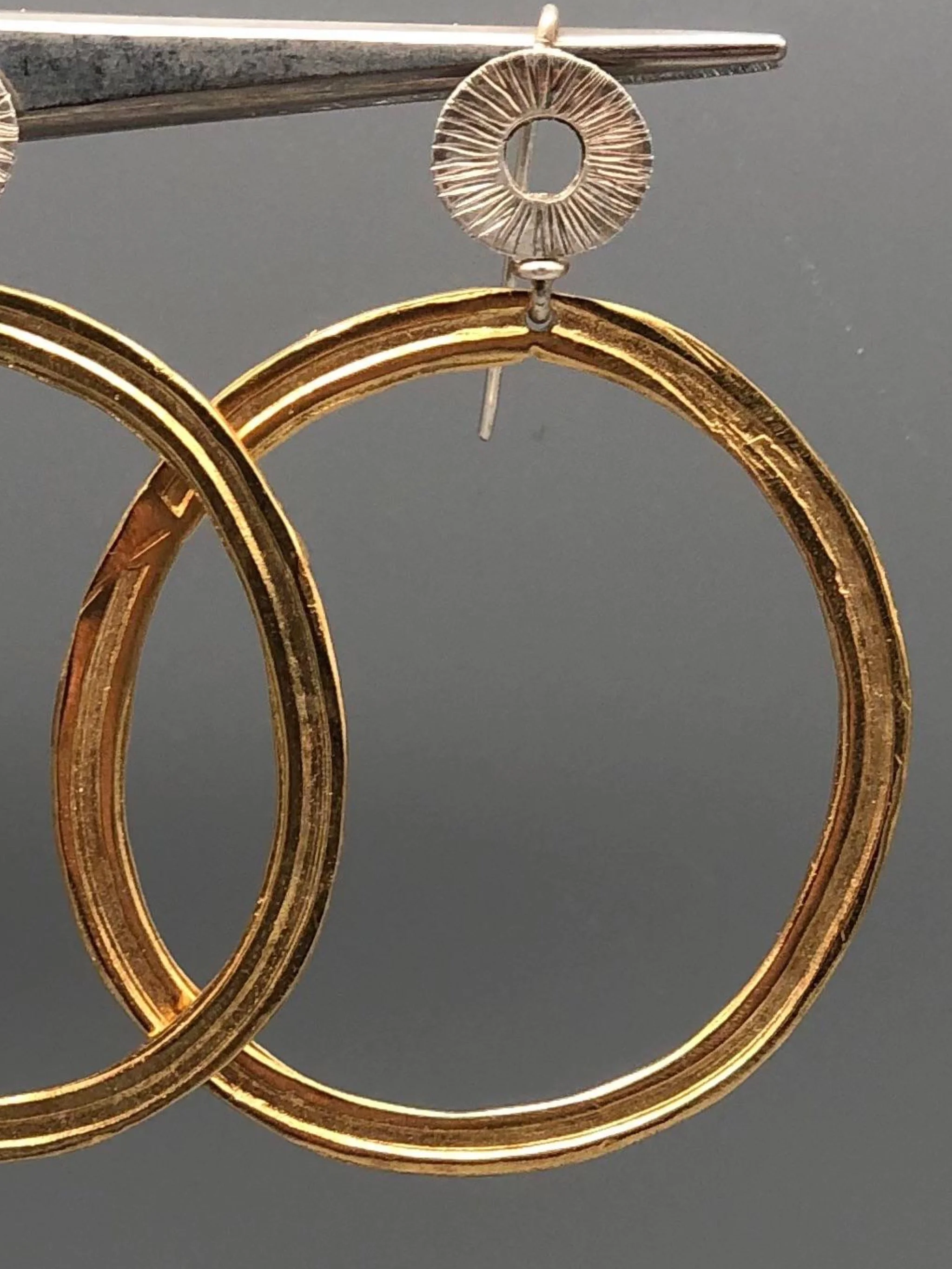 Dettaglio superficie incisa orecchini cerchio bronzo dorato e argento Gabriel Reinoso Crepundia Bologna