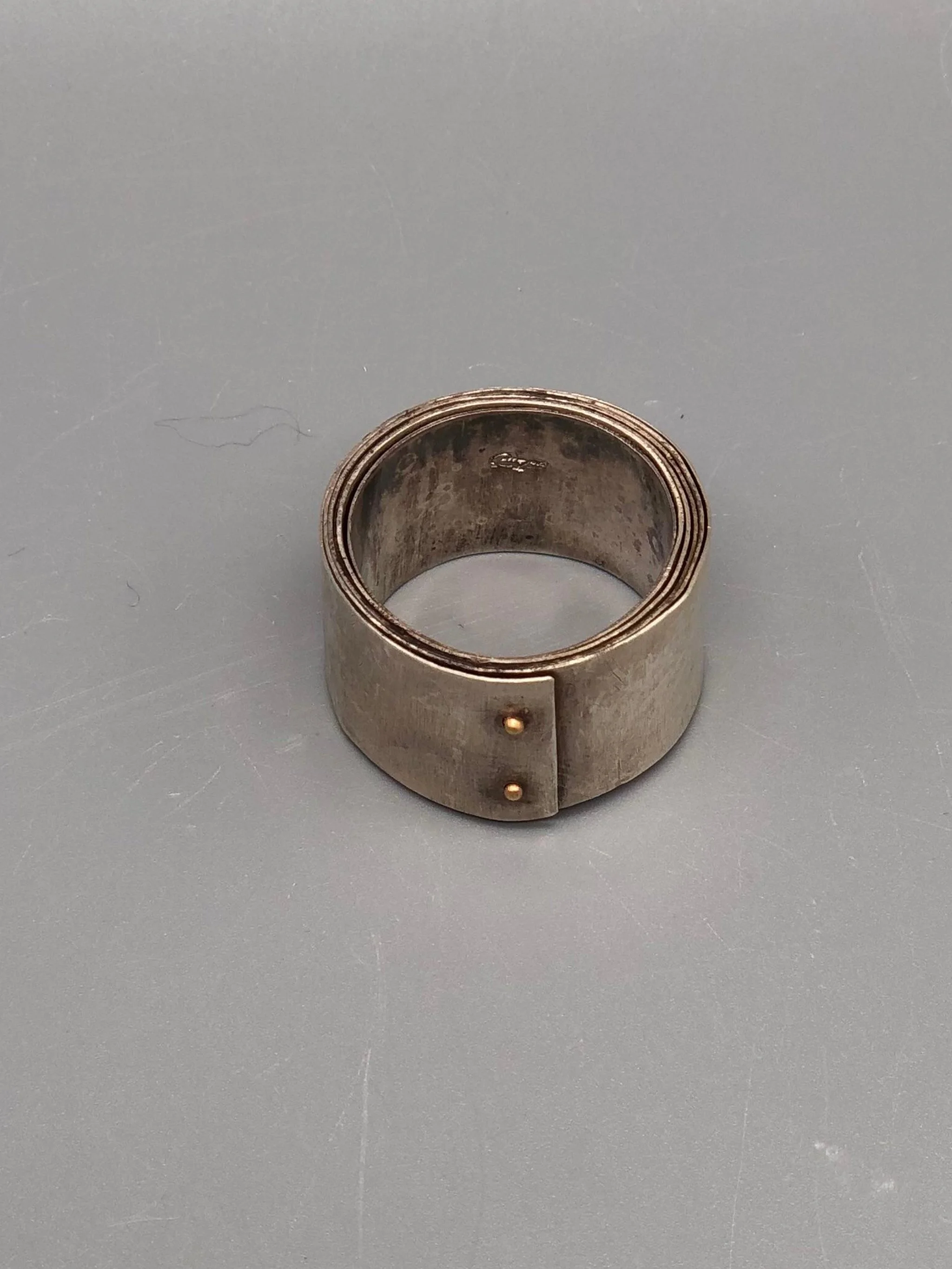 Girella ring by Mangàni in silver, featuring a wide coiled band accented with two small gold nails.