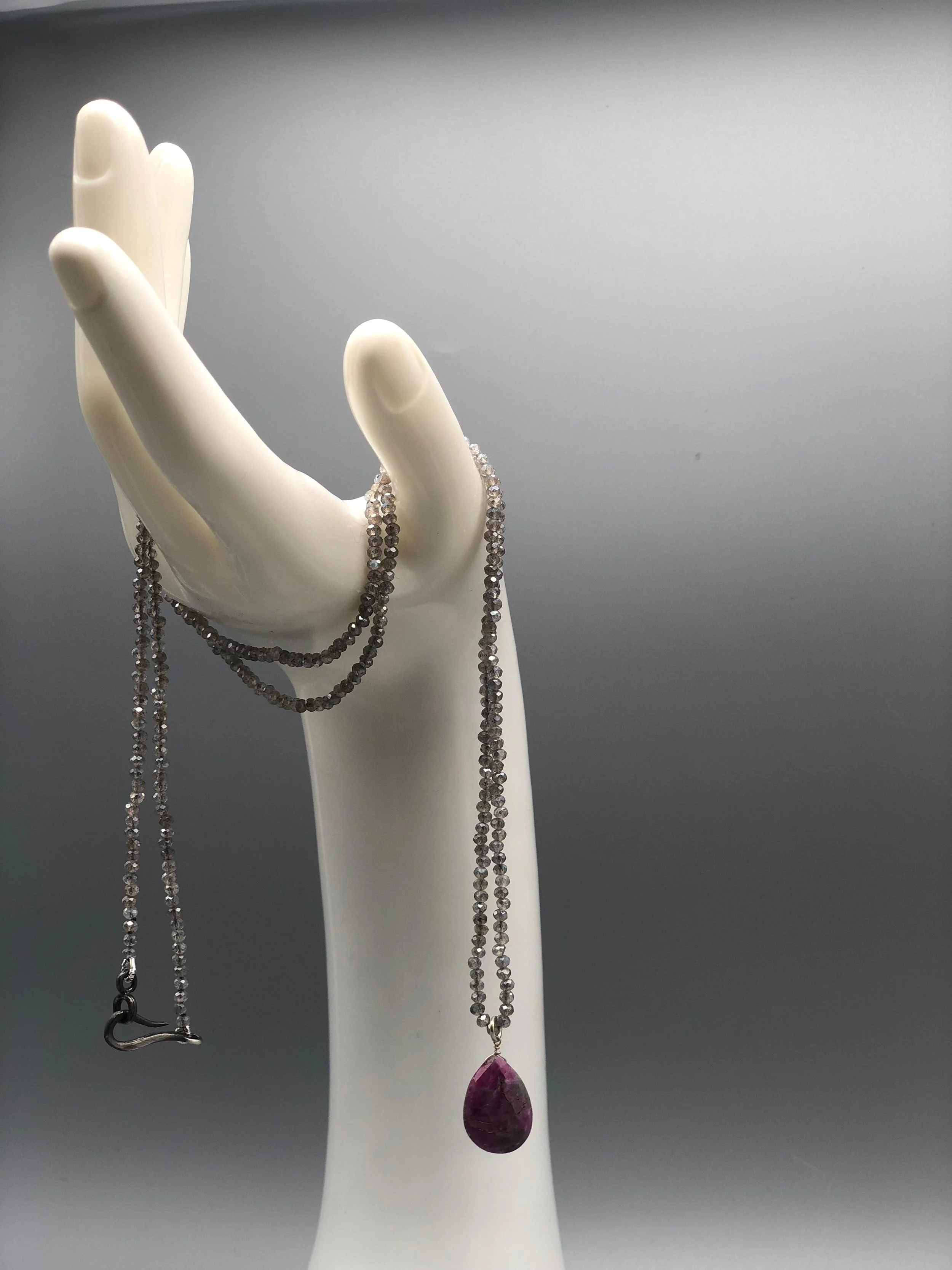 Collana con pietre in labradorite naturali e goccia in radice di rubino, composizione lineare design contemporaneo Crepundia Gioielli — Crepundia Bologna /
Necklace with natural labradorite gemstones and ruby root drop pendant, linear composition con