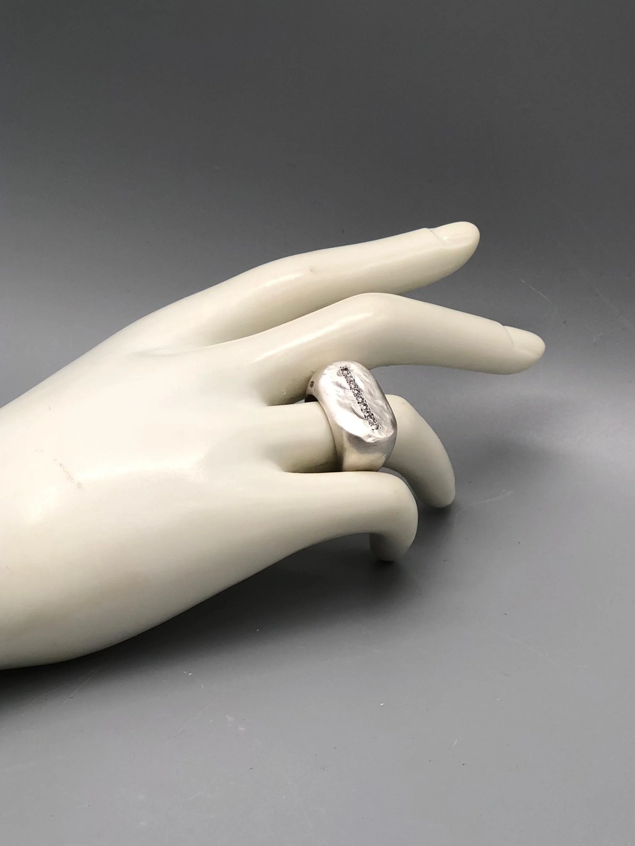Crepundia Gioielli New Echo ring in matte silver with a line of diamonds.
