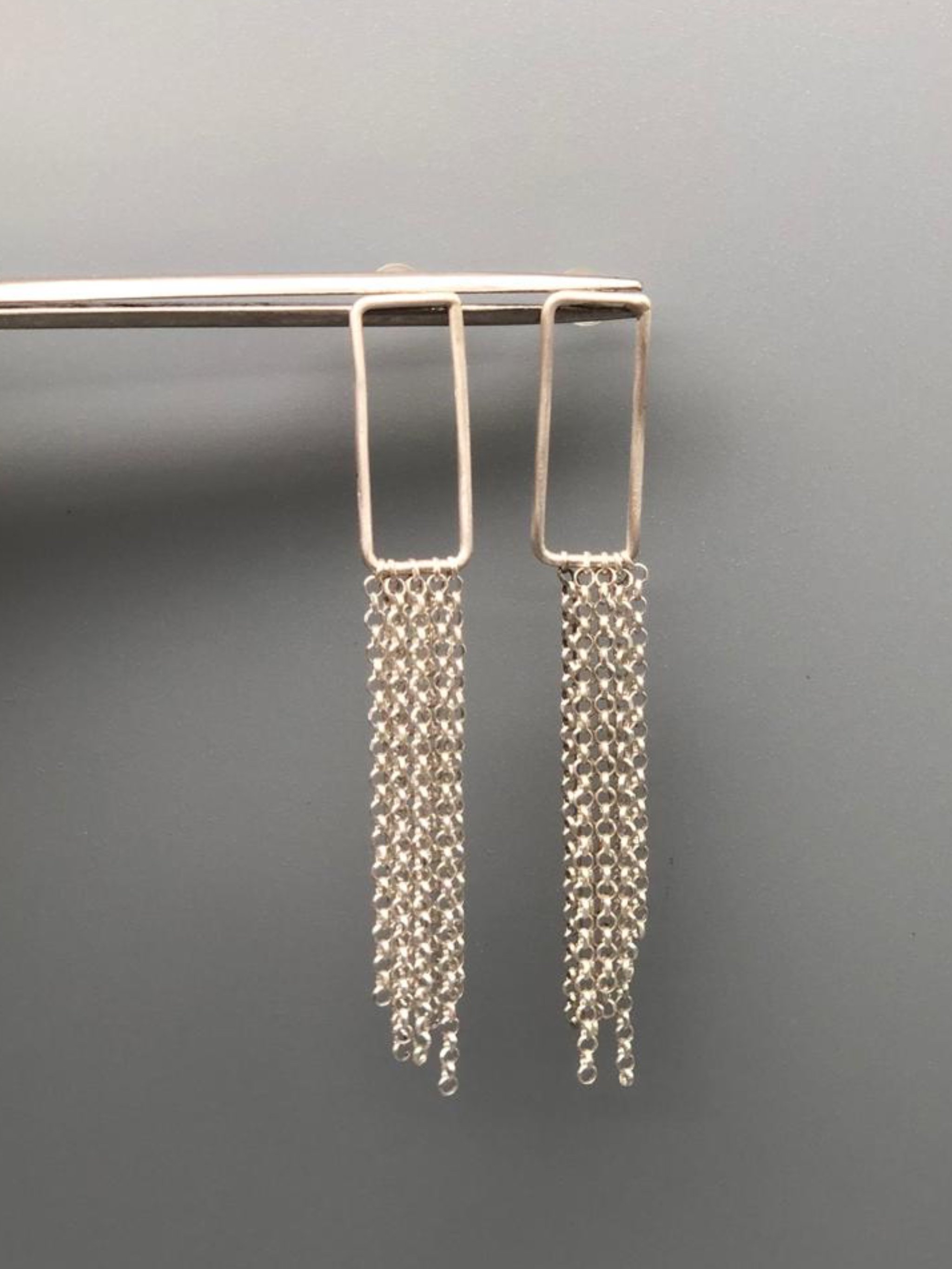 Orecchini Cascade Frame in argento 925 con struttura rettangolare aperta e cascata di sottili catene.
