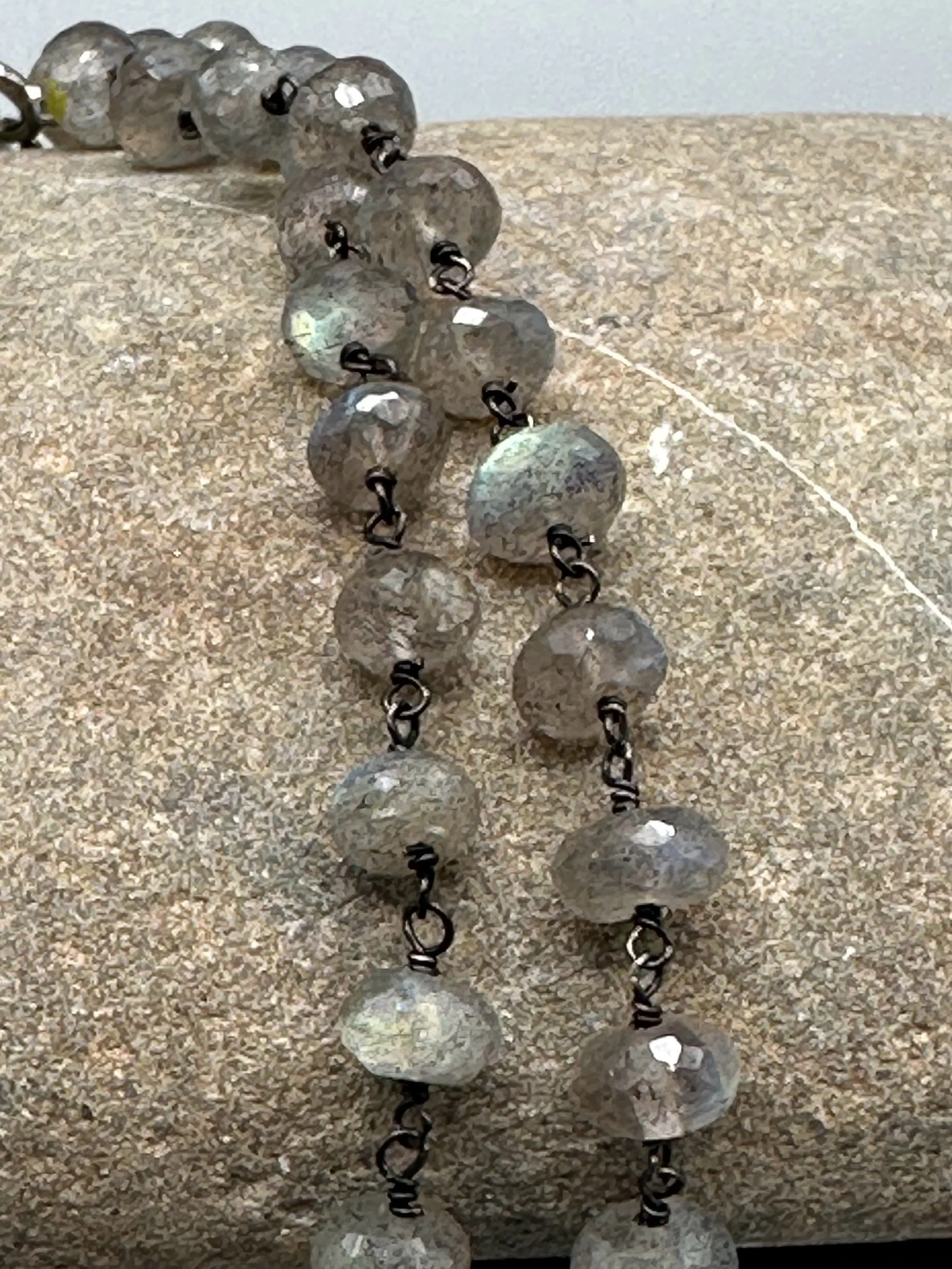 Collana Bold Labradorite con pietre naturali grigie sfaccettate e riflessi iridescenti. Bold Labradorite necklace with faceted grey gemstones and iridescent reflections.