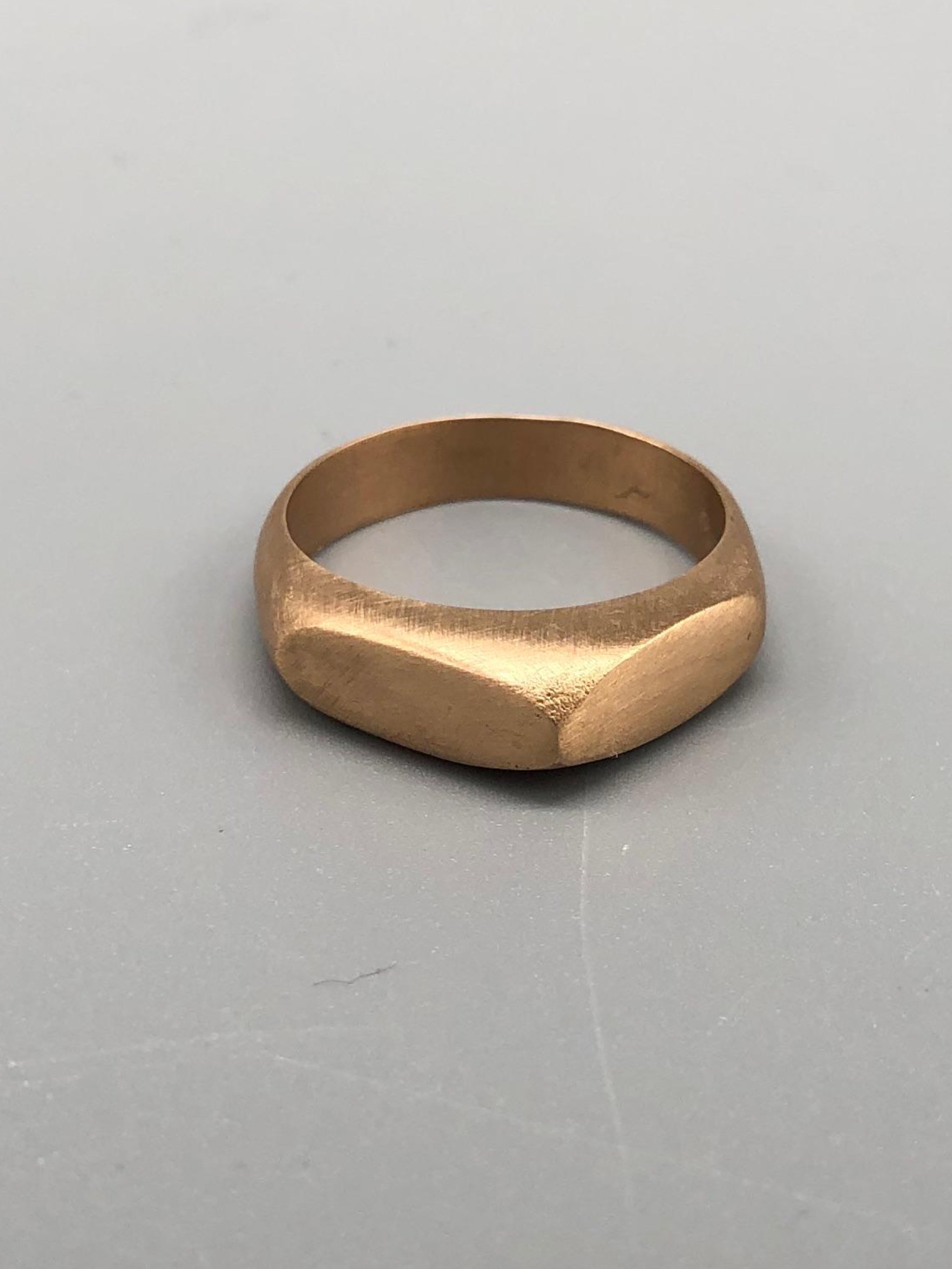 Anello Cuspide Crepundia in bronzo, con fascia geometrica, superfici sfaccettate e finitura satinata color oro caldo.  Crepundia Cuspide bronze ring featuring a geometric band, faceted surfaces and a