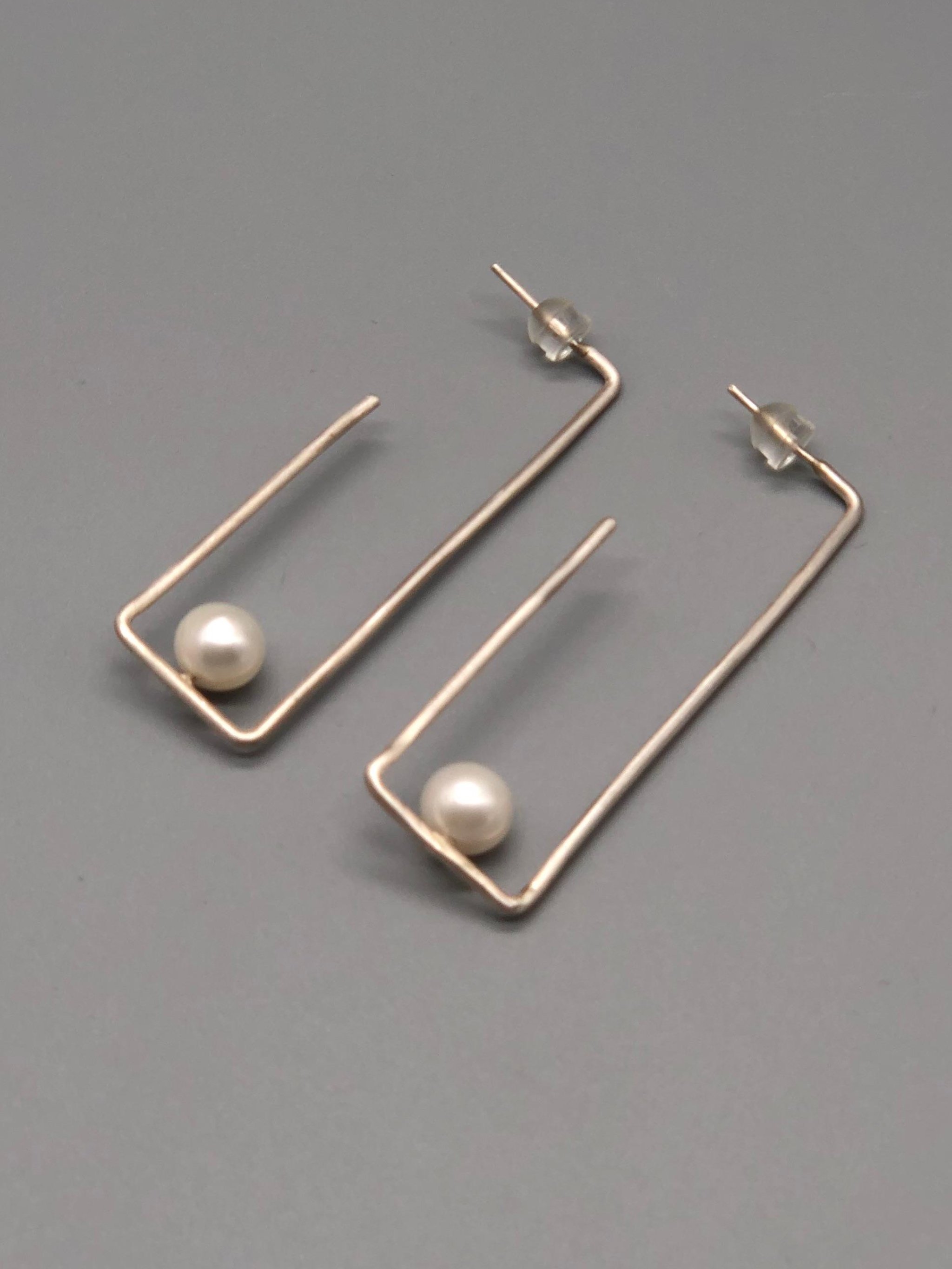 Crepundia Agadir earrings in silver with pearls, featuring an open, asymmetrical geometric design.