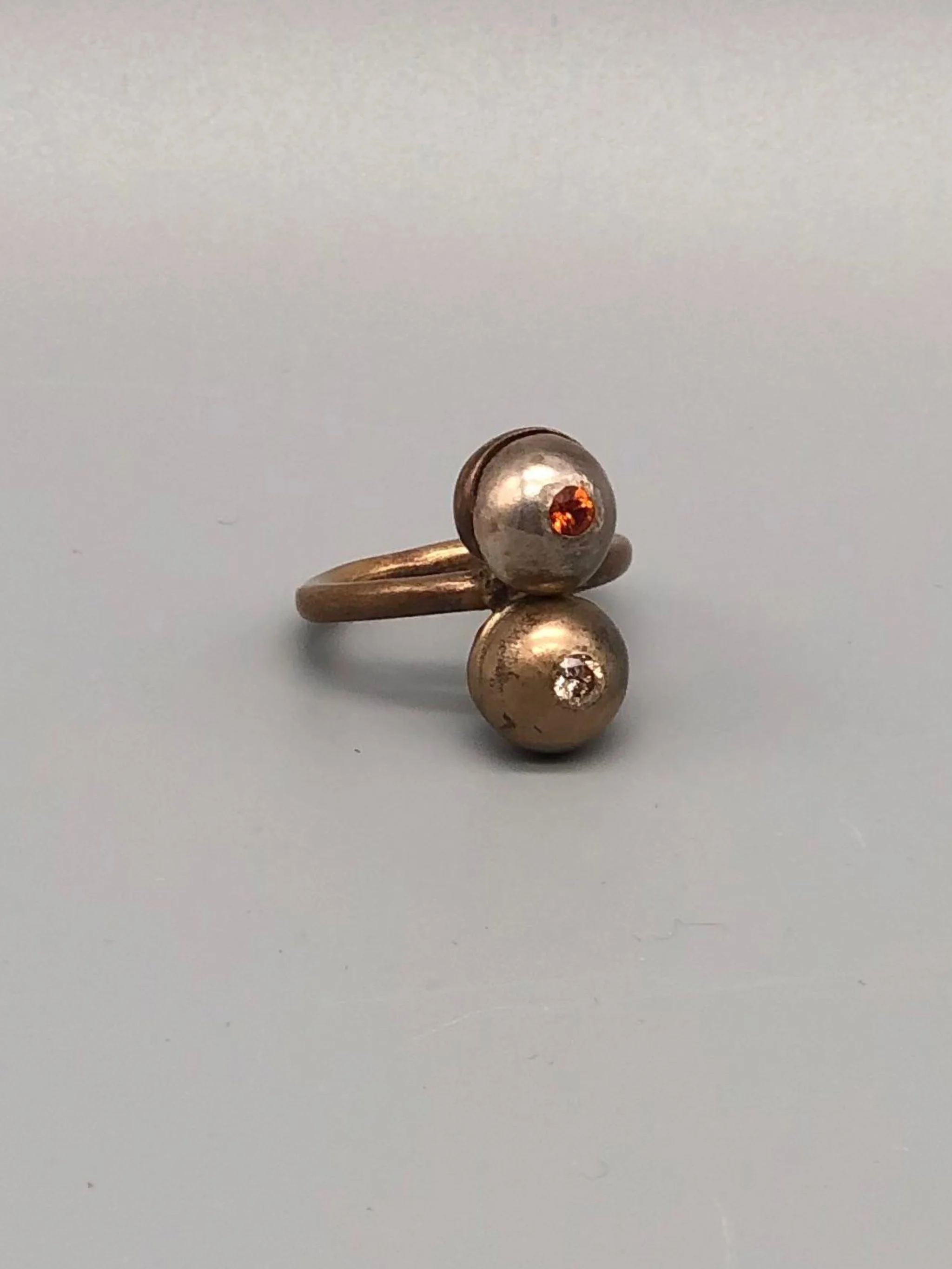 Riccardo Raimondi bronze ring with cognac quartz and spessartite garnet, double sphere design, contemporary jewelry Crepundia Gioielli Bologna