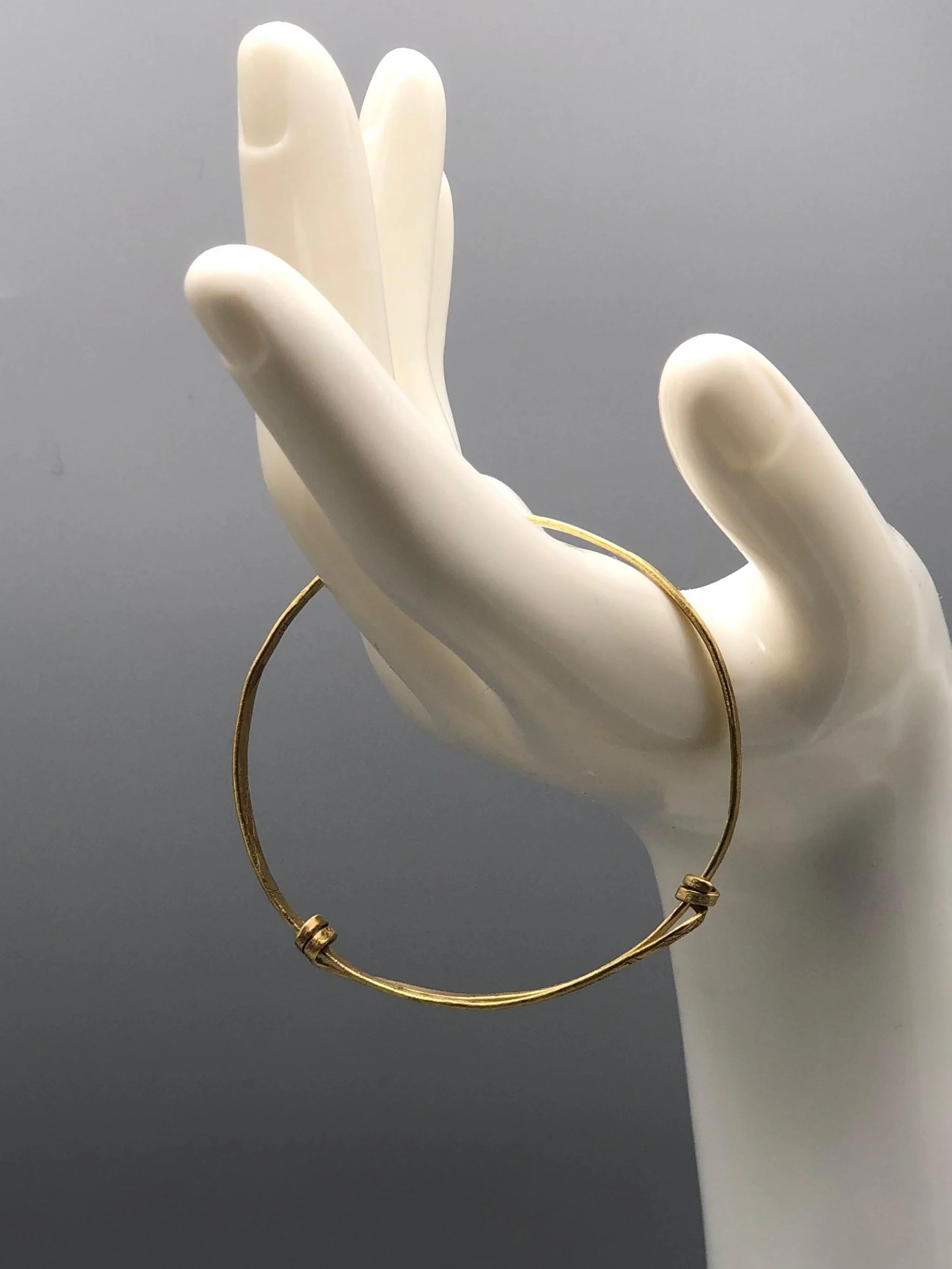 Bracciale Orbit in ottone inciso di Padma per Crepundia Gioielli Bologna, bracciale contemporaneo geometrico con nodi laterali e linea circolare essenziale.