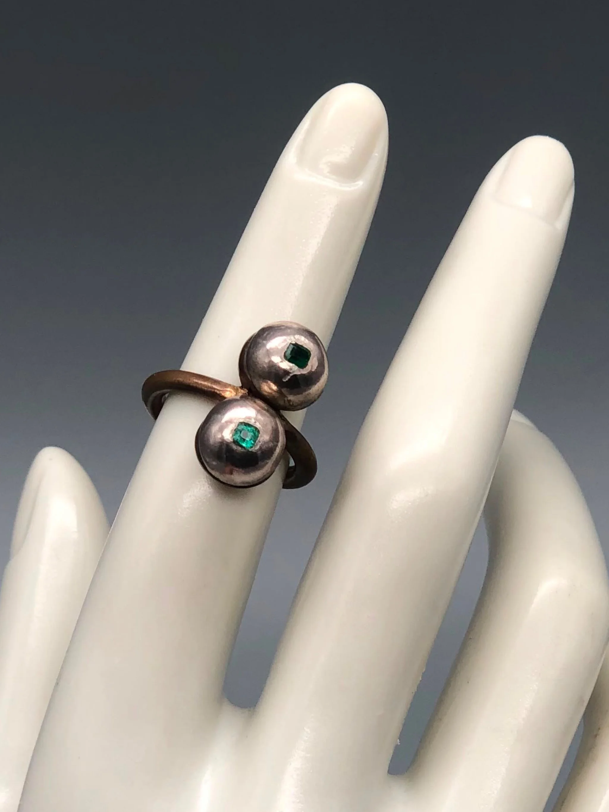 Raimondi ring in bronze and silver with two spherical elements and emeralds.