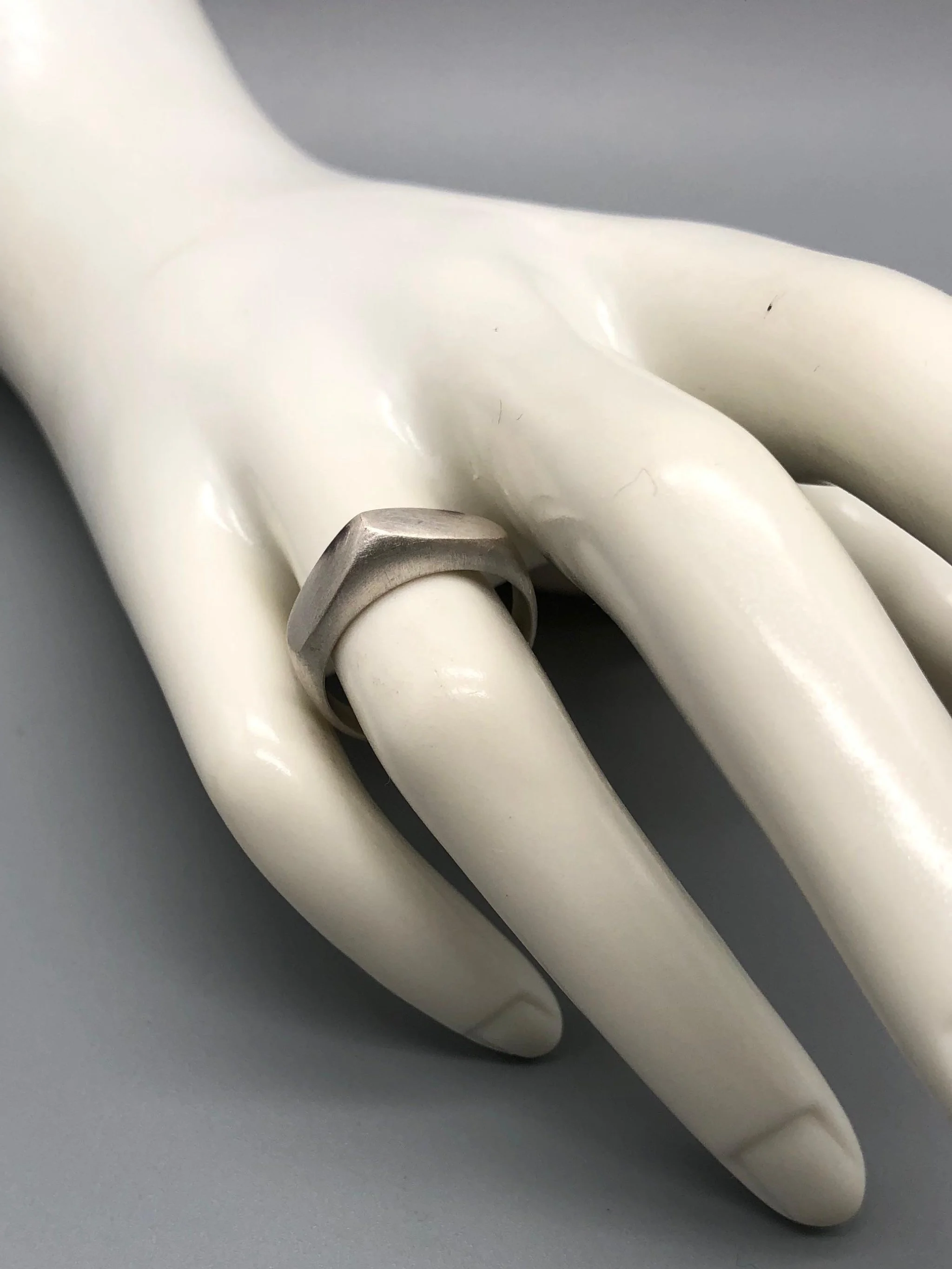 Anello Cuspide Crepundia in argento 925, con fascia geometrica, superfici sfaccettate e finitura satinata. Crepundia Cuspide ring in sterling silver 925, featuring a geometric band, faceted surface