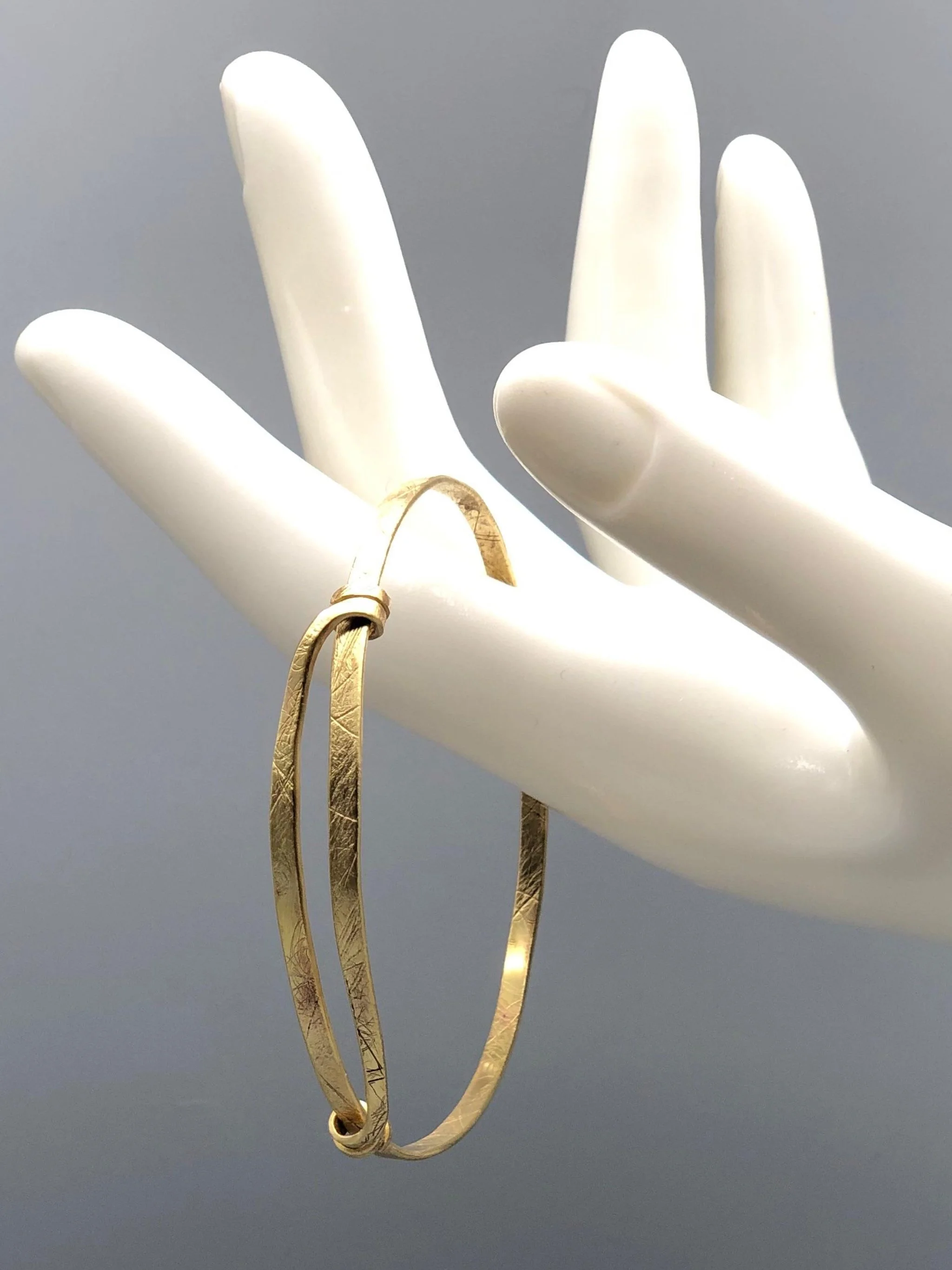 Bracciale Orbit in ottone inciso di Padma per Crepundia Gioielli Bologna, bracciale contemporaneo geometrico con nodi laterali e linea circolare essenziale.