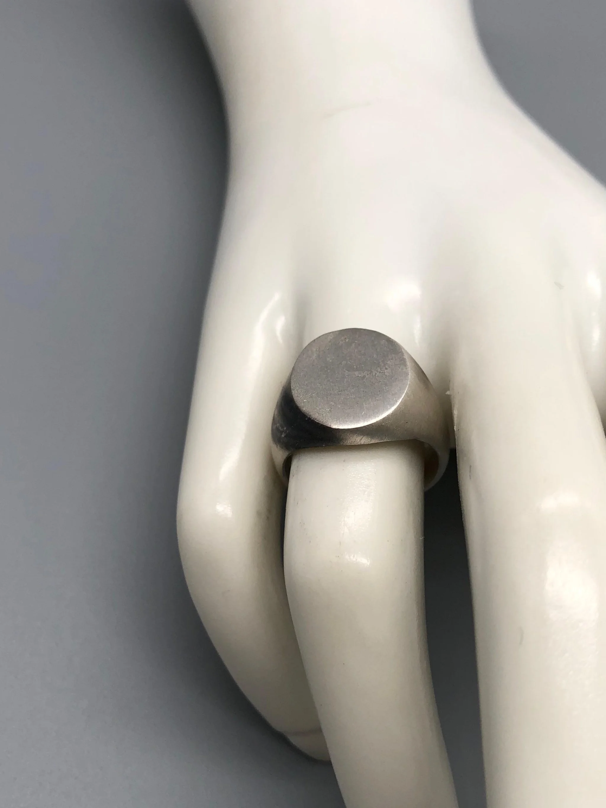 Anello Chevalière in argento opaco, gioiello contemporaneo dal volume pieno e dal design essenziale. Chevalière ring in matte silver, contemporary jewellery with a solid volume and essential design.