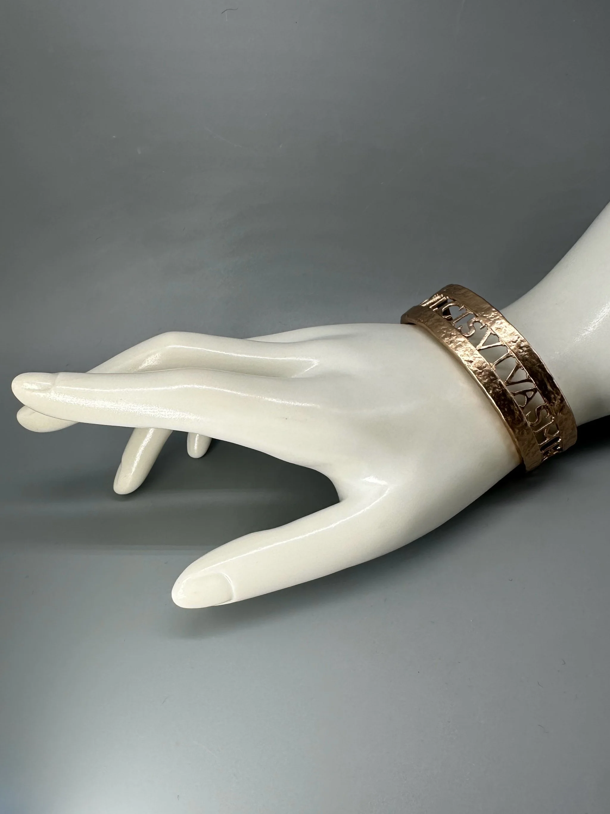 Bracciale Anima Dulcis di CōDICEDS in bronzo bocciardato, aperto e regolabile, con iscrizione latina traforata.  CōDICEDS Anima Dulcis open adjustable cuff in hammered bronze with openwork Latin inscr