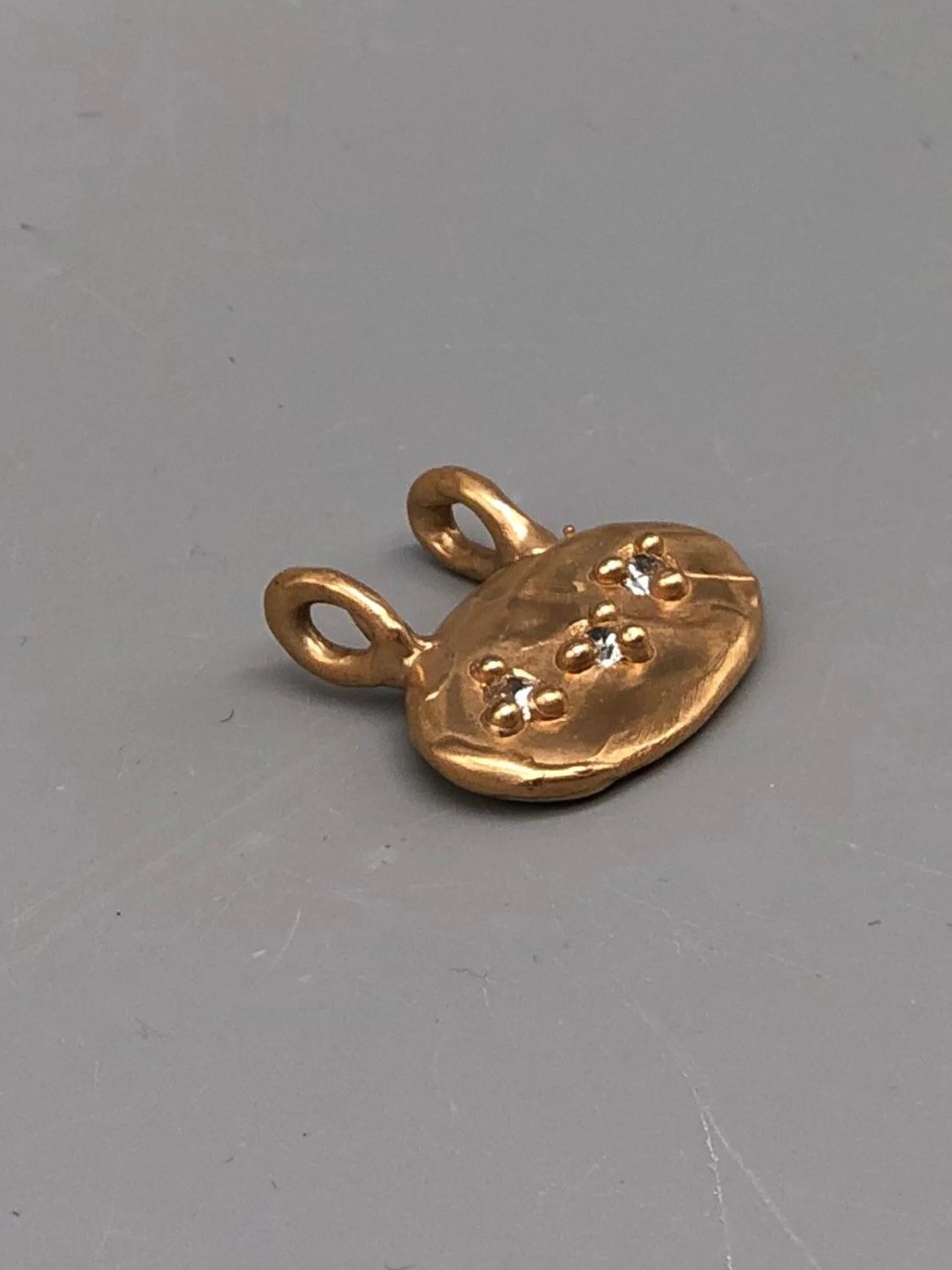 Oval bronze pendant with three zircon stones by Floret Gioielli.