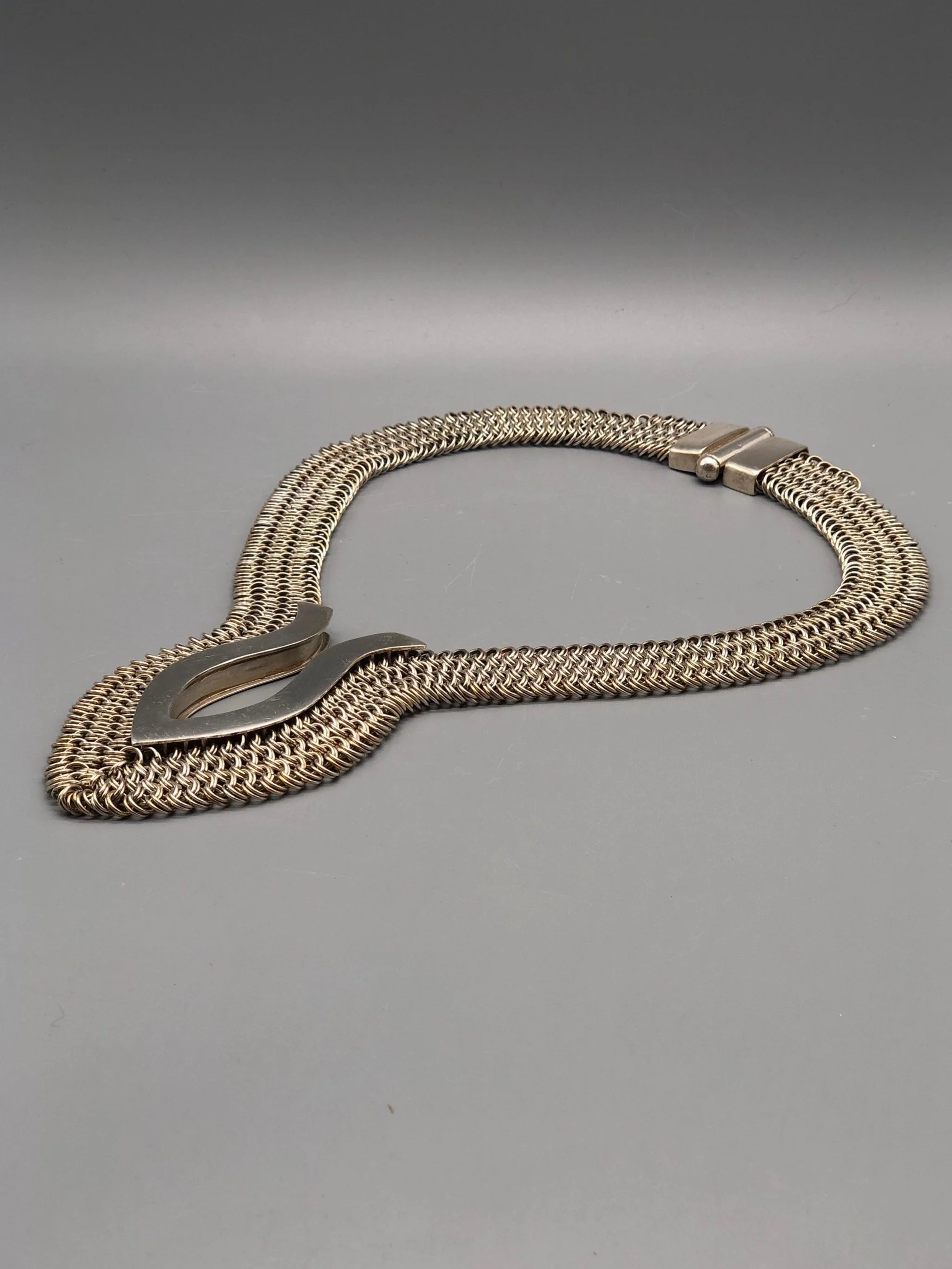 Piscis necklace by Ariadna Segafredo, crafted in woven metal mesh with a sculptural clasp for Crepundia Gioielli.