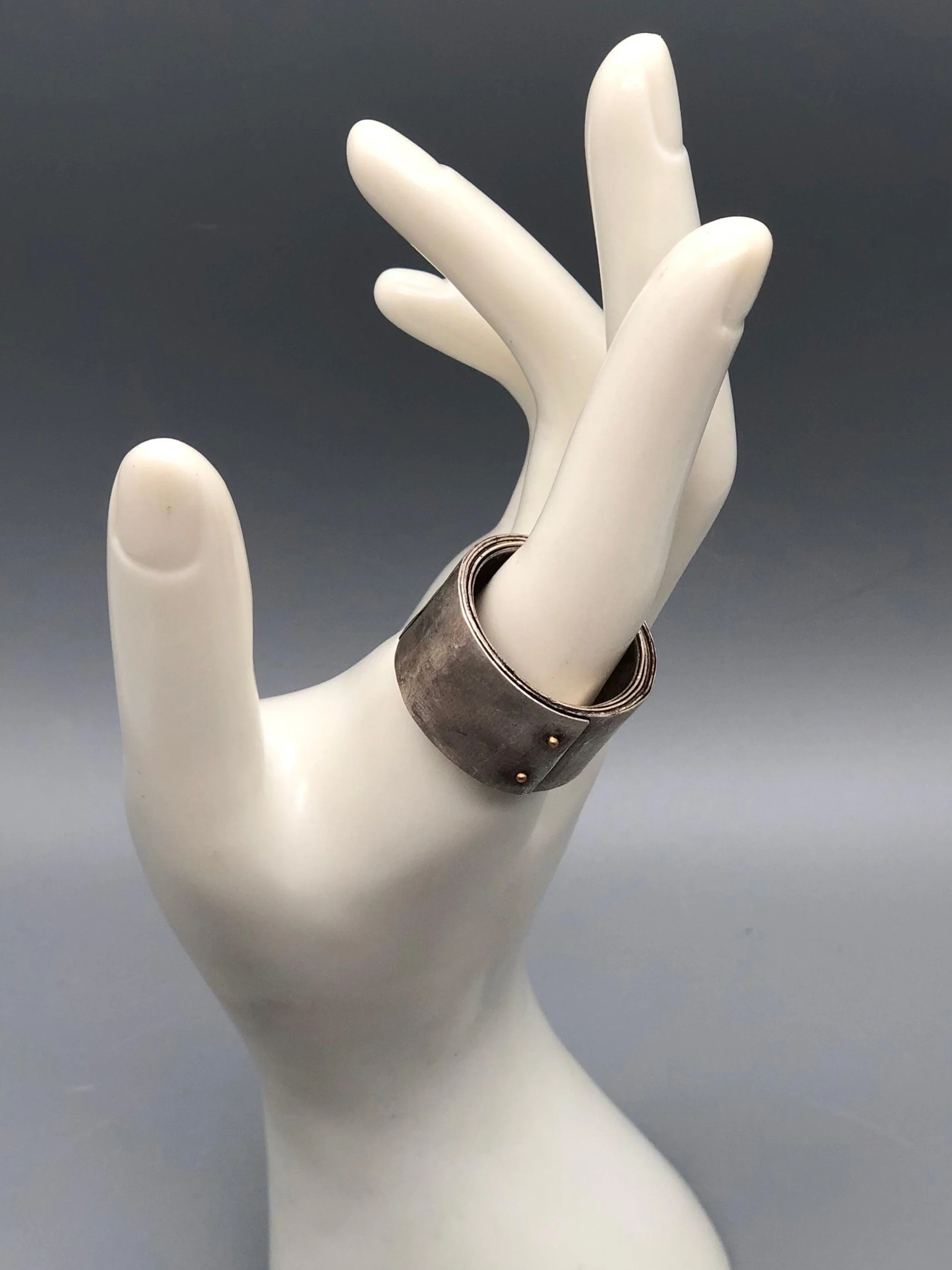 Girella ring by Mangàni in silver, featuring a wide coiled band accented with two small gold nails.