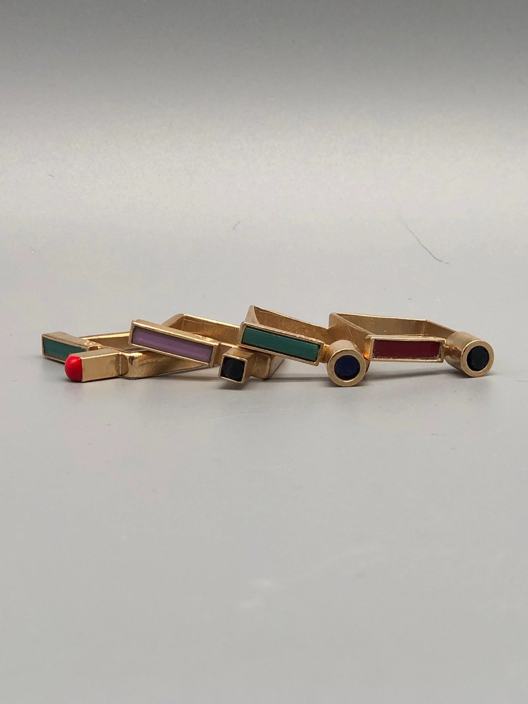 Contemporary rings by EL Gioielli for Crepundia Gioielli Bologna, geometric gold-toned rings with colored enamel details displayed on neutral background and worn on hand