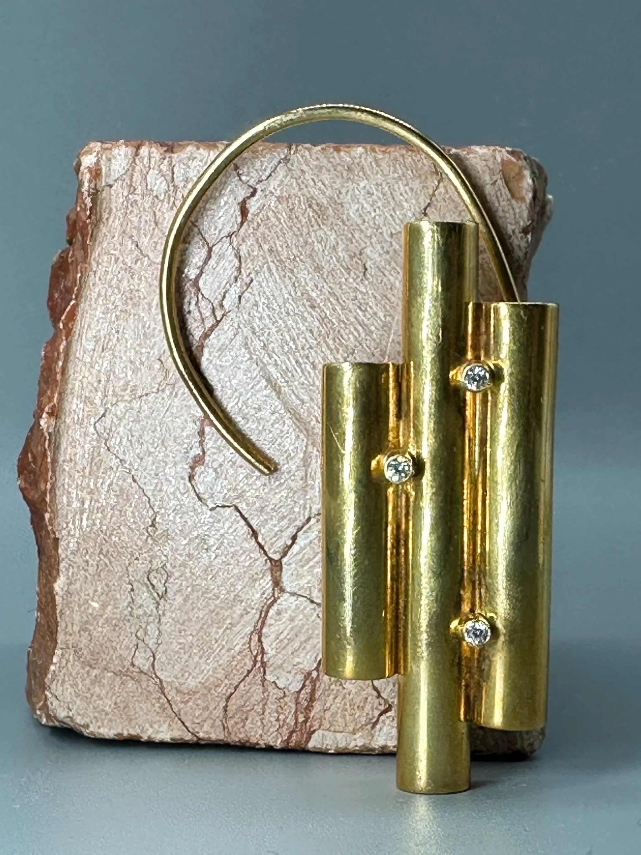 The Earcuff di HoAsen, ear cuff dorato con cilindri asimmetrici. The Earcuff by HoAsen, gold-tone ear cuff with asymmetrical cylinders.