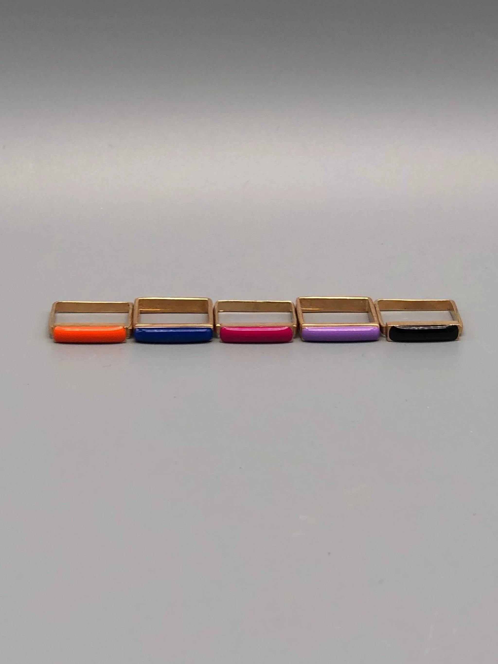 Slim enamel rings in bronze with gold finish, available in black, orange, pink, cornflower blue and purple enamel, Crepundia Gioielli Bologna.