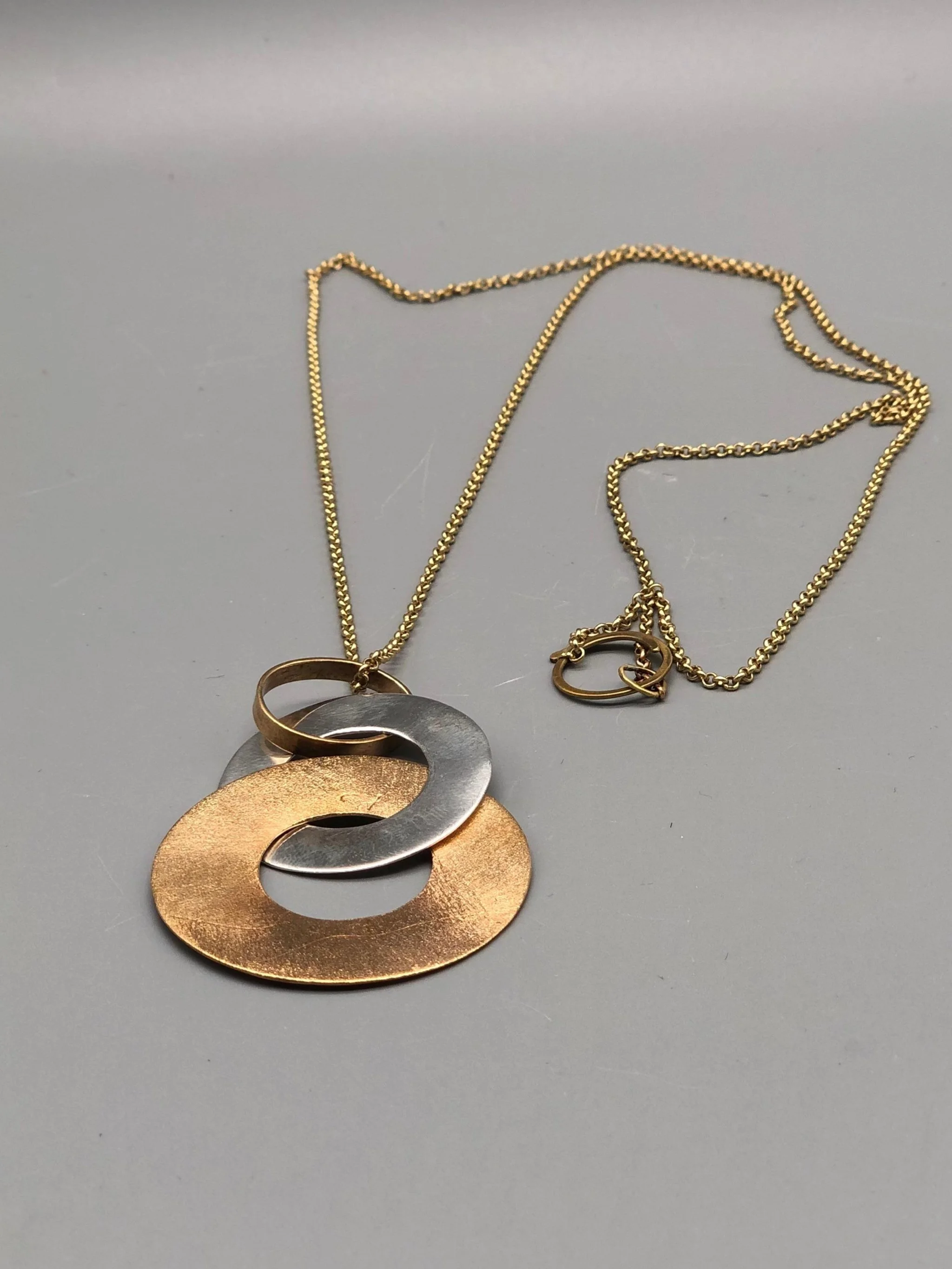 Pendente Dischi Intrecciati di Padma per Crepundia Gioielli Bologna in argento e similoro con catena in ottone