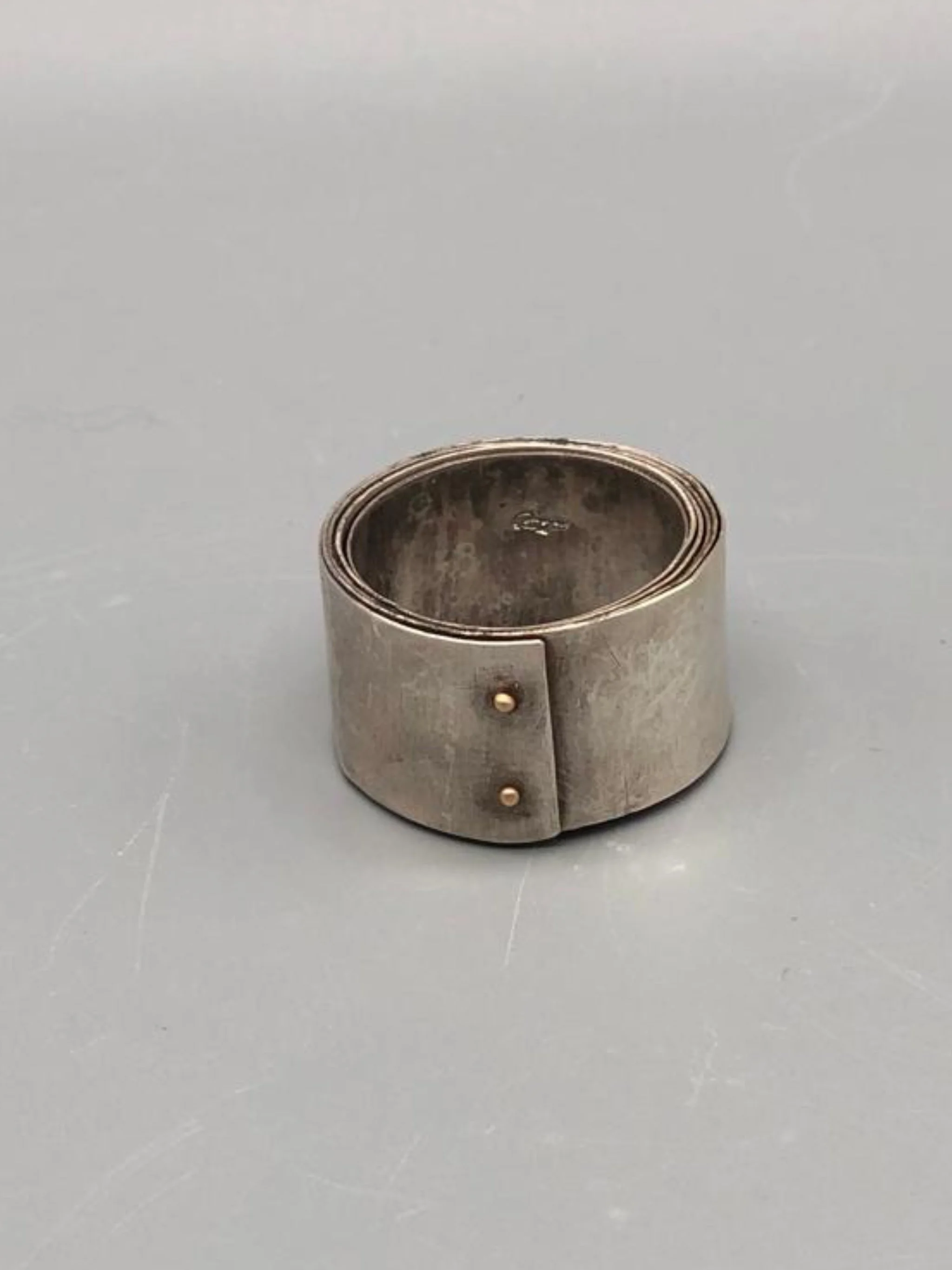 Girella ring by Mangàni in silver, featuring a wide coiled band accented with two small gold nails.