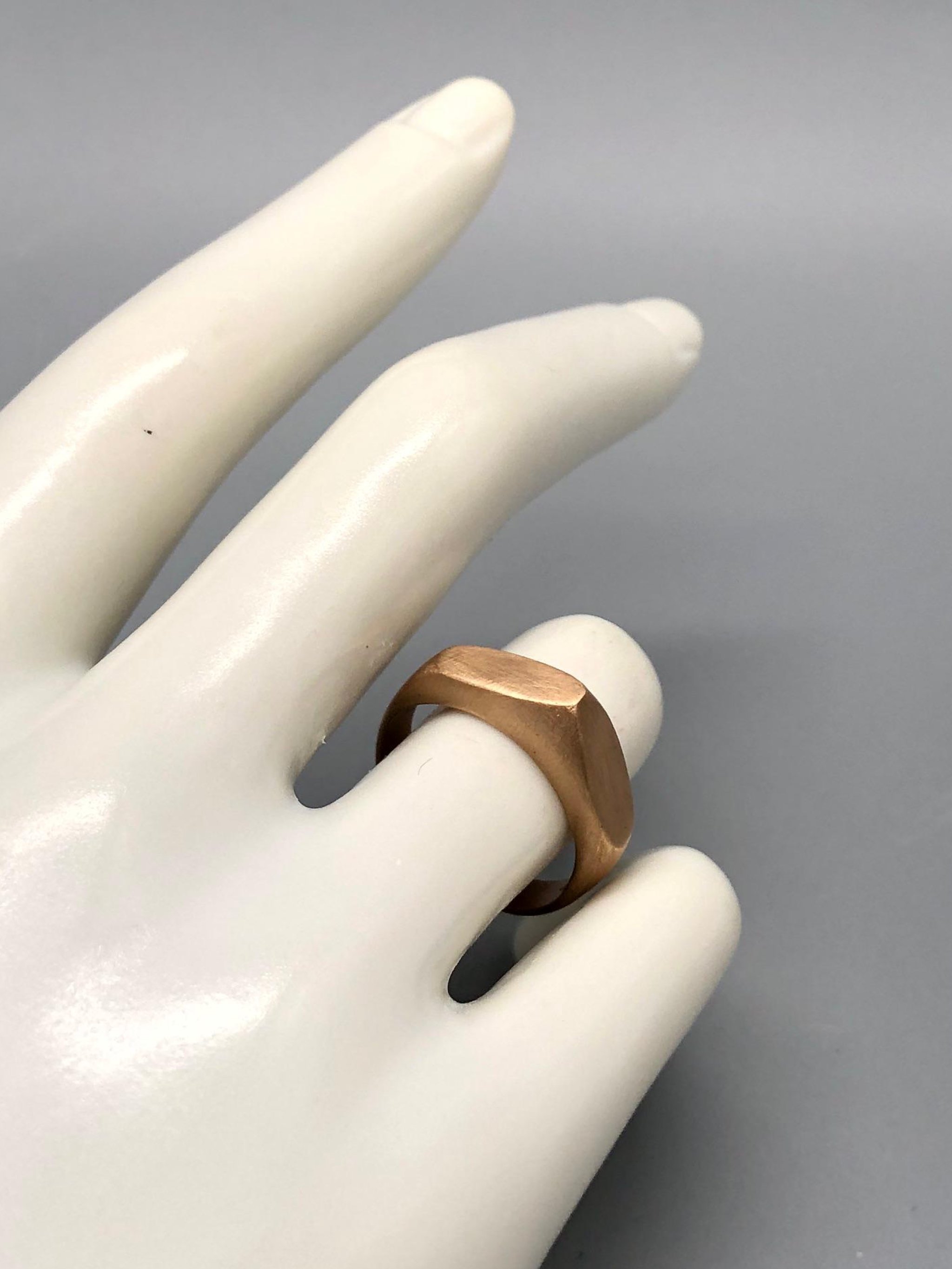 Anello Cuspide Crepundia in bronzo, con fascia geometrica, superfici sfaccettate e finitura satinata color oro caldo.  Crepundia Cuspide bronze ring featuring a geometric band, faceted surfaces and a