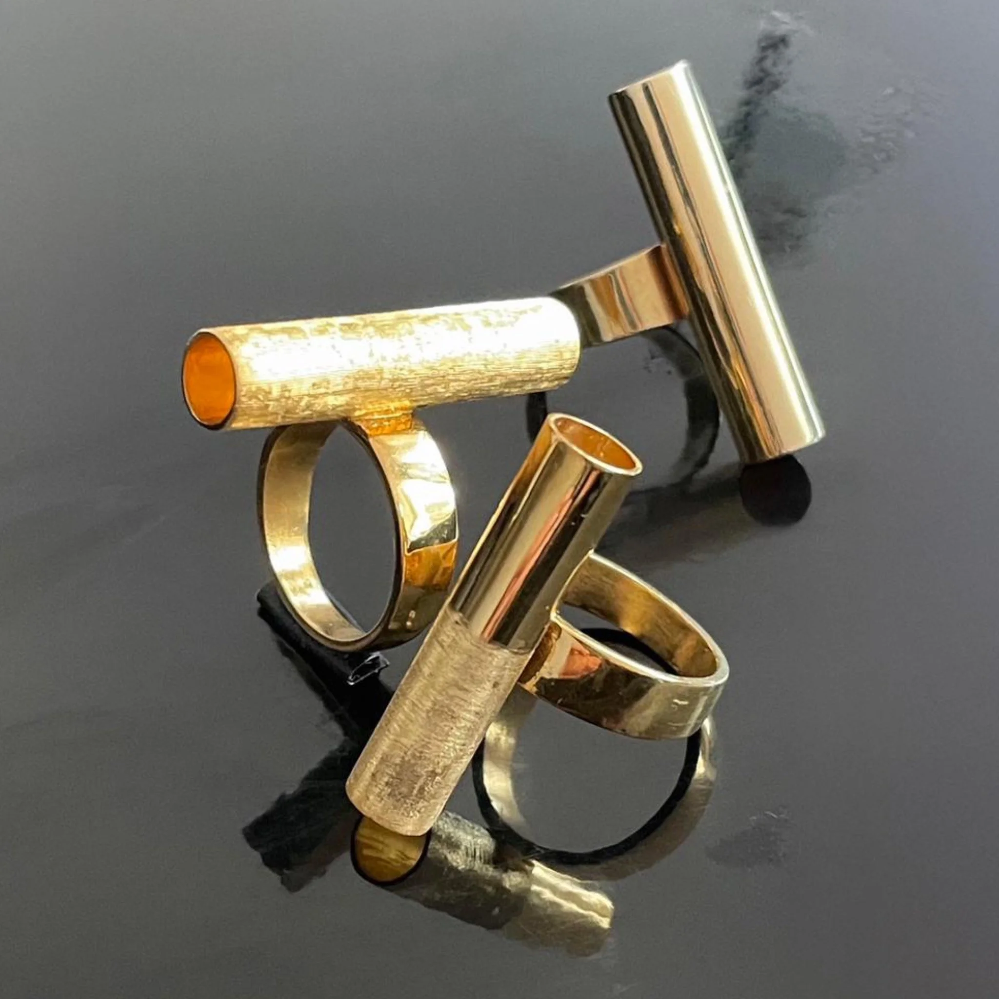 Gold plated silver tube rings with different surface finishes, sculptural geometric design — HoAsen Jewelry by Tiziana Scalzo — Crepundia Bologna, variation between polished, matte and textured surfaces
