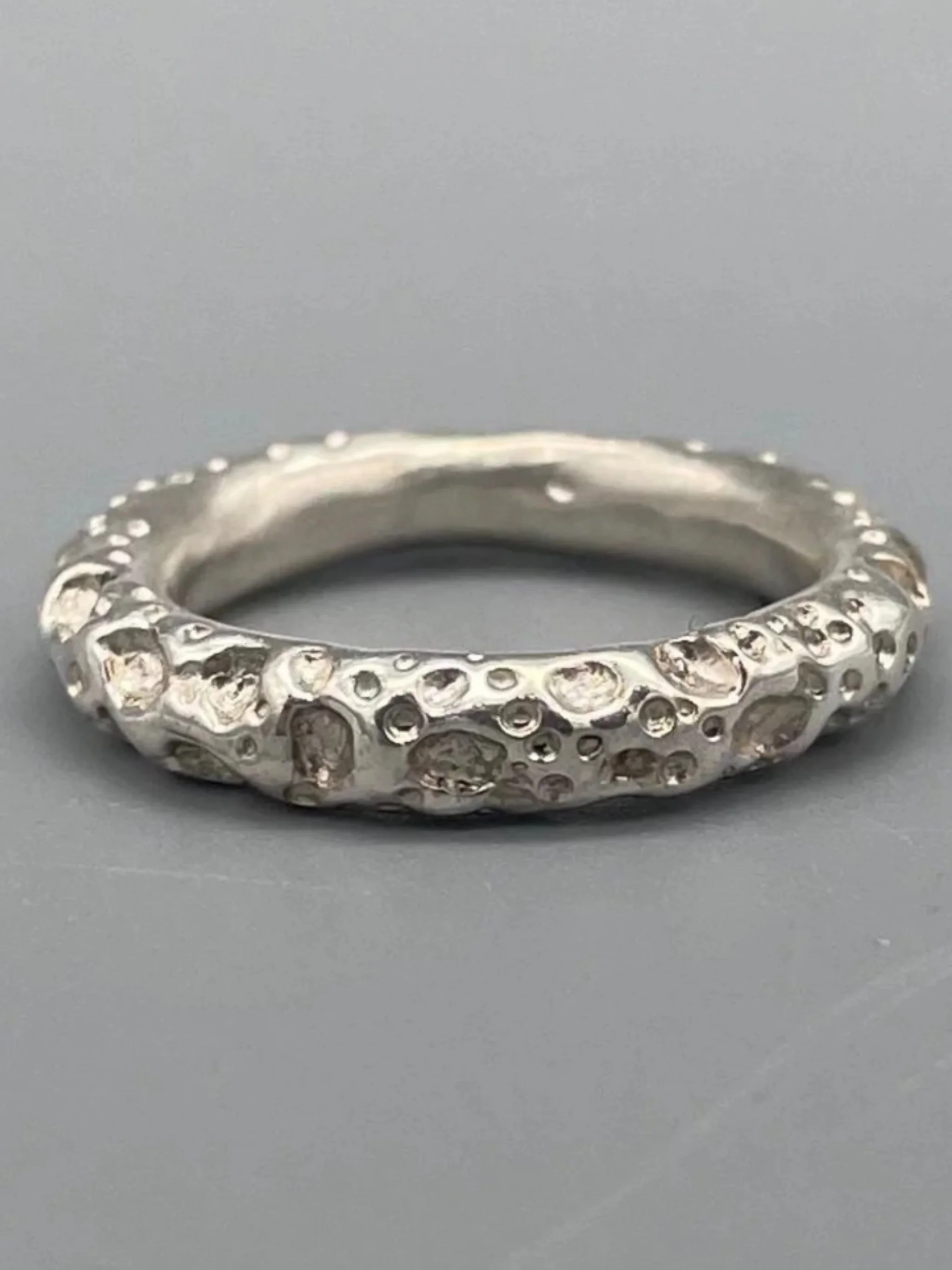 Anello Fede Lunare Portas Jewels argento 925 dettaglio superficie puntinata e irregolare design contemporaneo Crepundia Gioielli — Crepundia Bologna, close-up textured silver ring with cratered finish