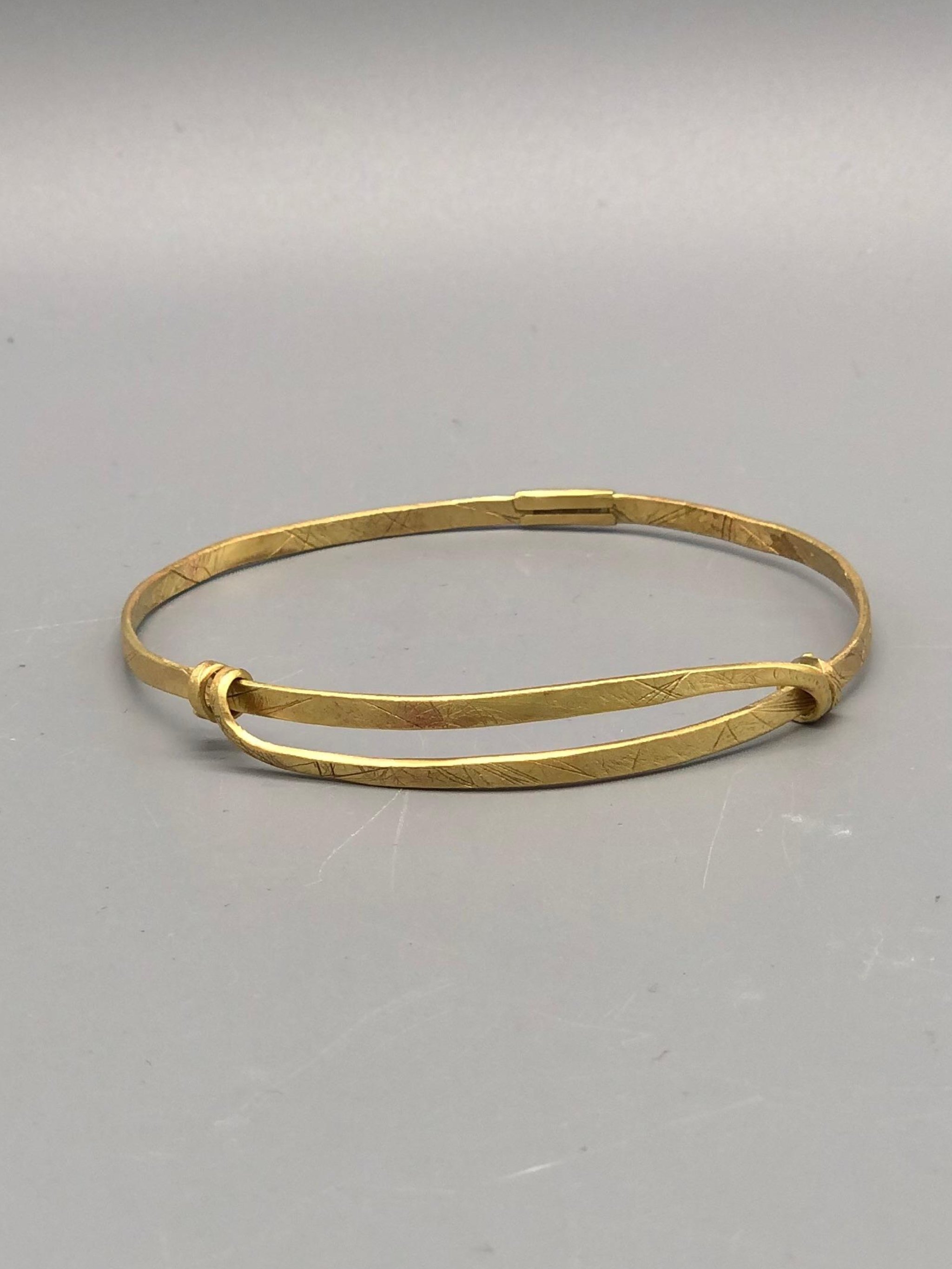 Bracciale Orbit in ottone inciso di Padma per Crepundia Gioielli Bologna, bracciale contemporaneo geometrico con nodi laterali e linea circolare essenziale.