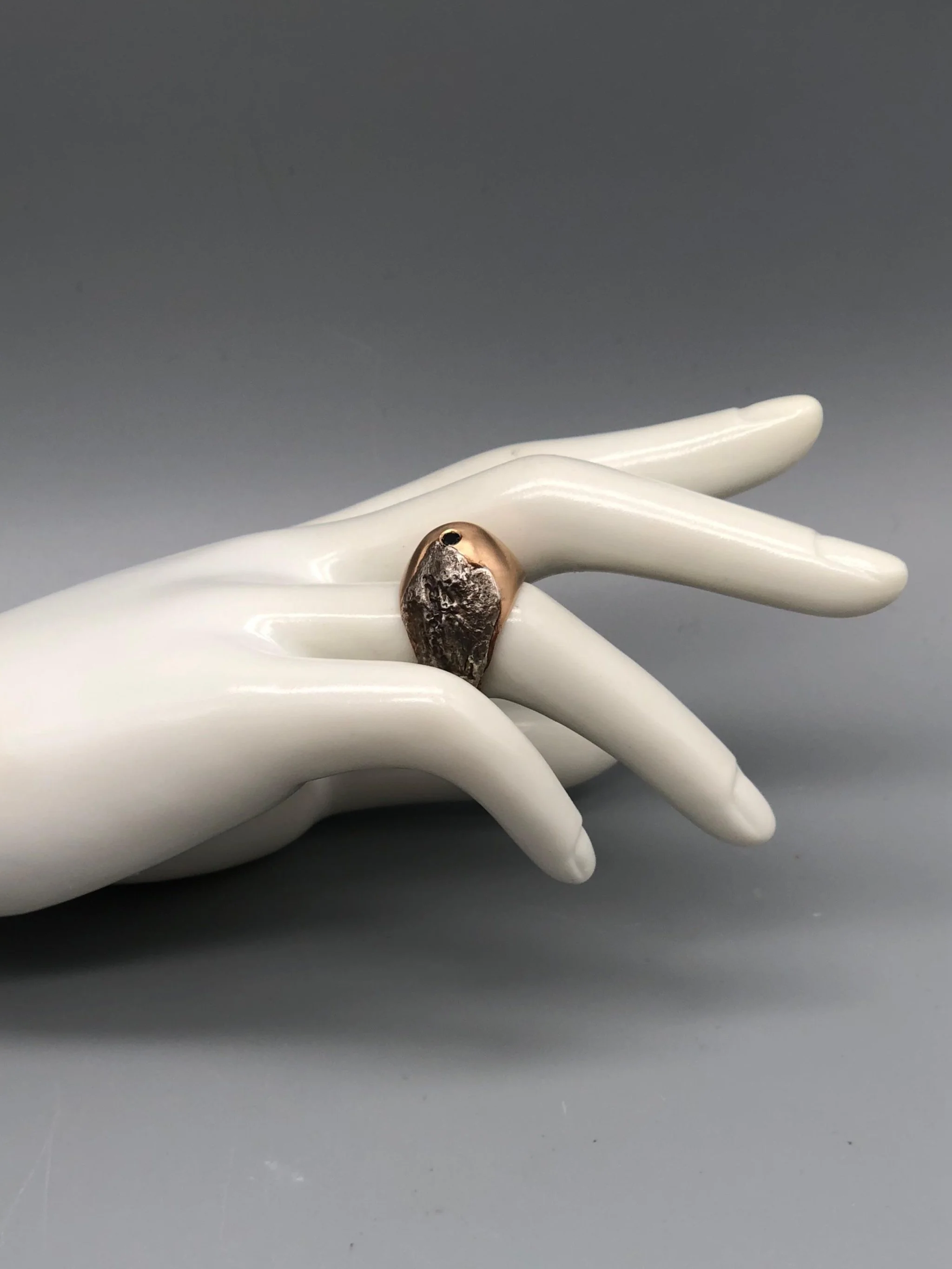 Padma Hill ring in rose bronze with raw silver application, garnet and black zircon. Sculptural contemporary handmade ring available at Crepundia Gioielli Bologna.