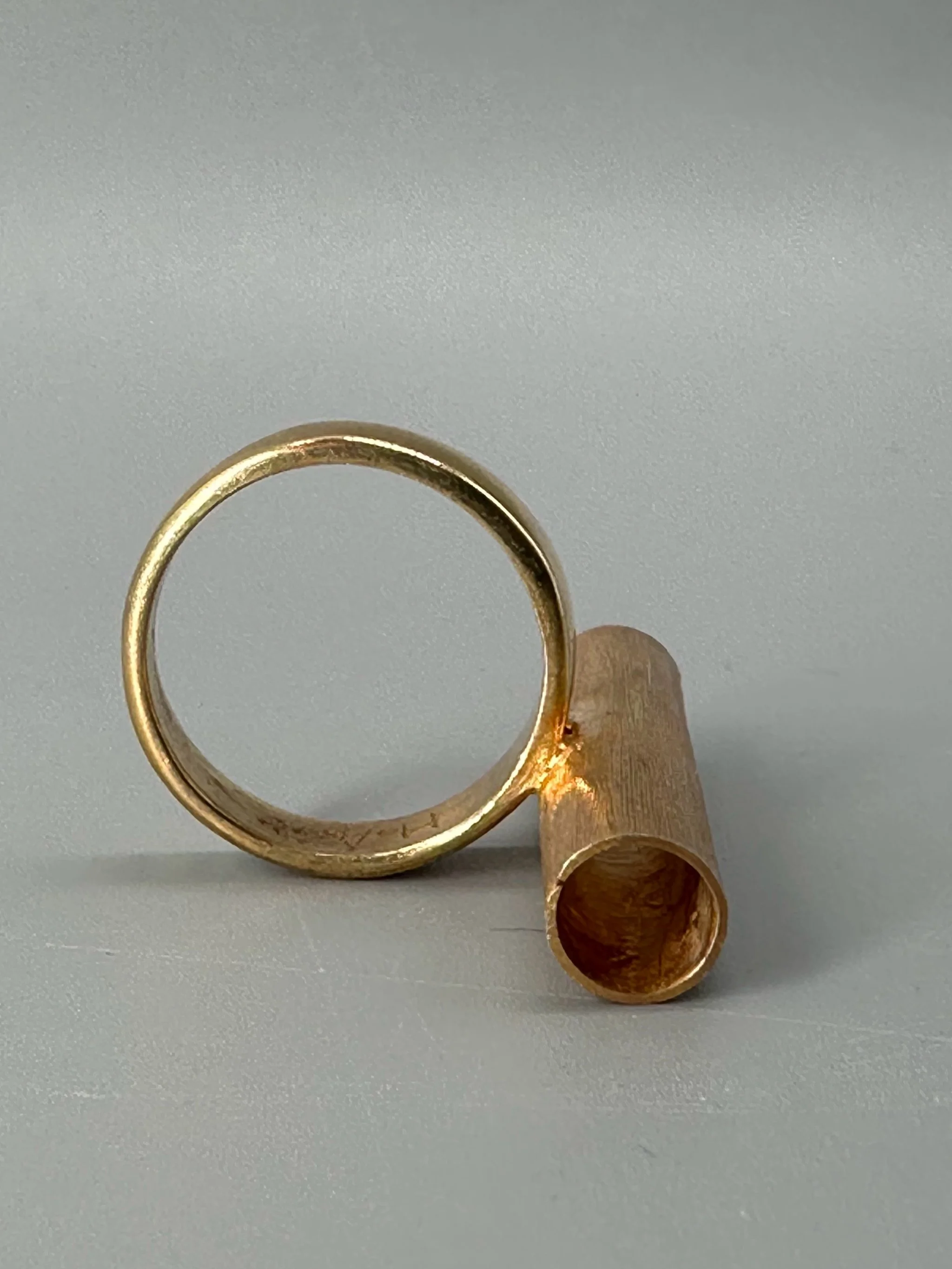 Anello Rough Tube di HoAsen Jewelry in argento dorato satinato, con elemento tubolare inciso.  Rough Tube ring by HoAsen Jewelry in satin-finished gold-plated silver, with a textured tubular element.