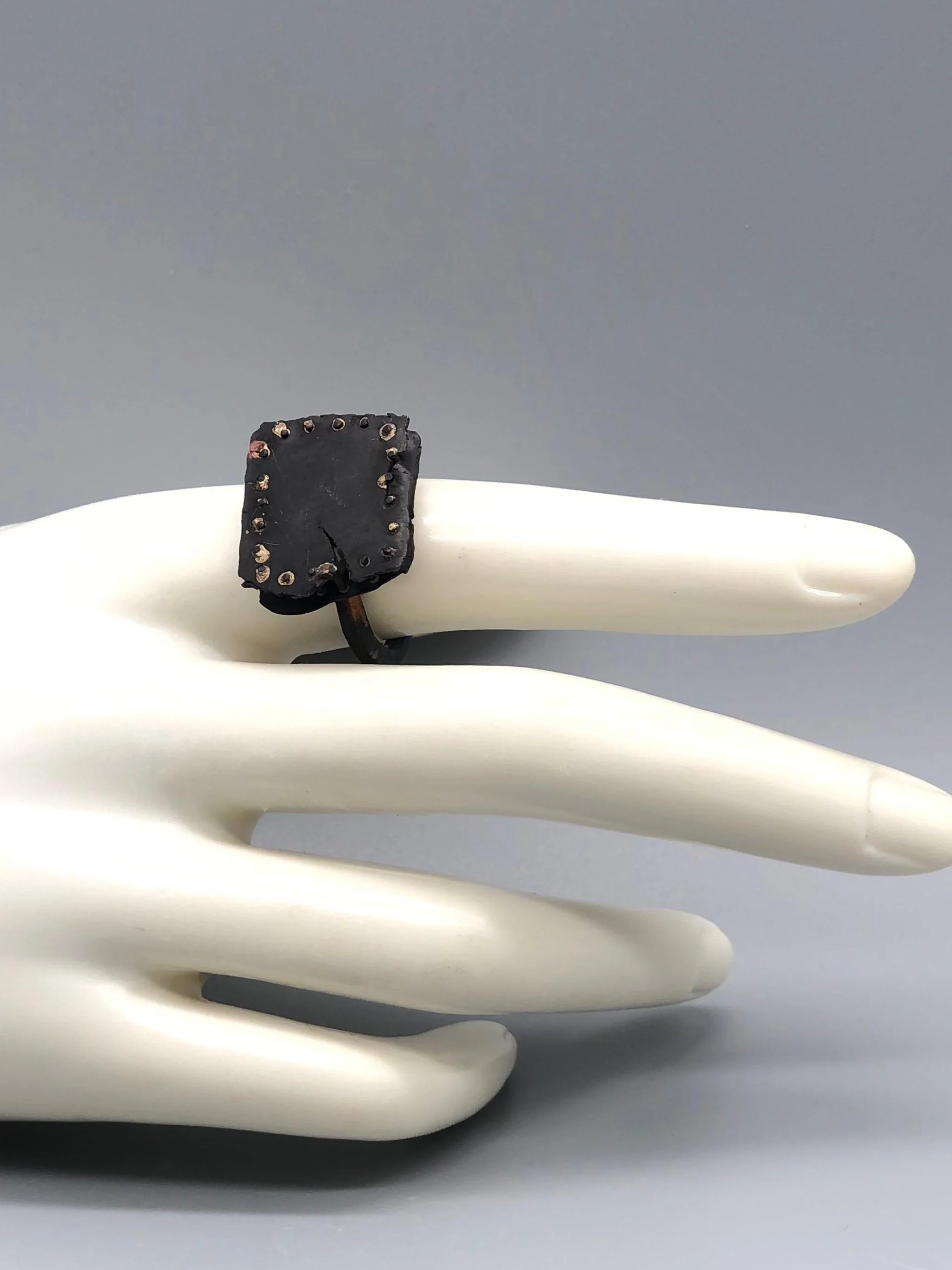 Anello Gabbia di Marco Mangàni in oro 14 kt e oro 18 kt ossidato, con struttura a sbarre e due diamanti grigi nascosti all’interno.