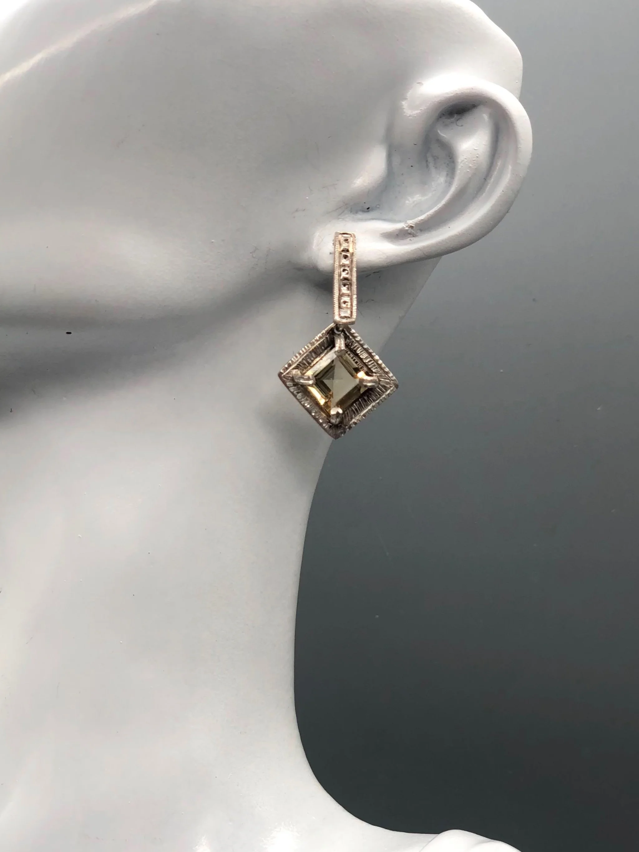 Orecchini Vedado in argento lavorato e quarzo citrino sfaccettato, con pietra montata a rombo. Vedado earrings in textured silver and faceted citrine quartz, with a diamond-shaped setting.