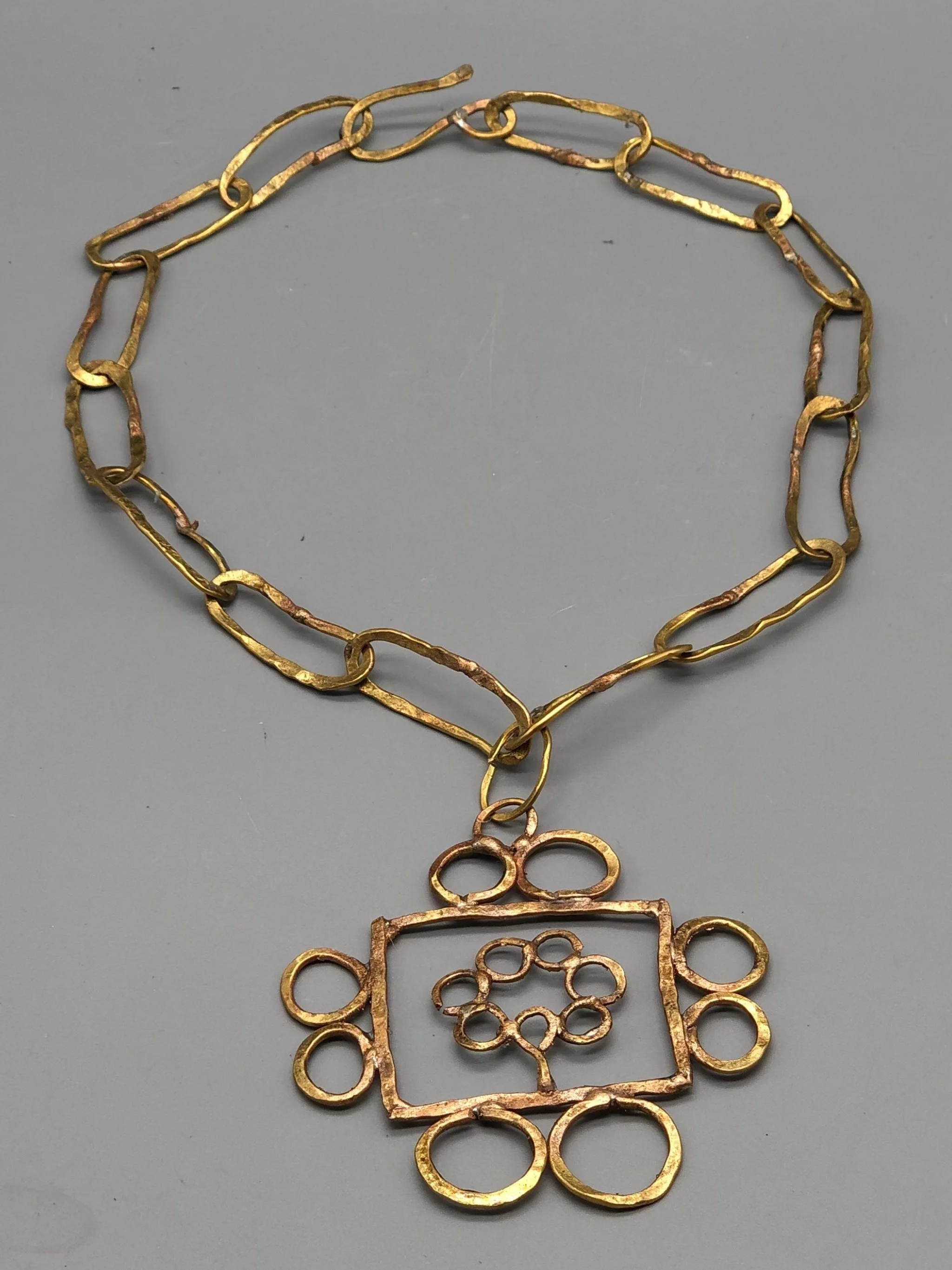 Collana Tree Frame di Claudia Cuzzeri in ottone opaco con maglie irregolari e pendente geometrico.