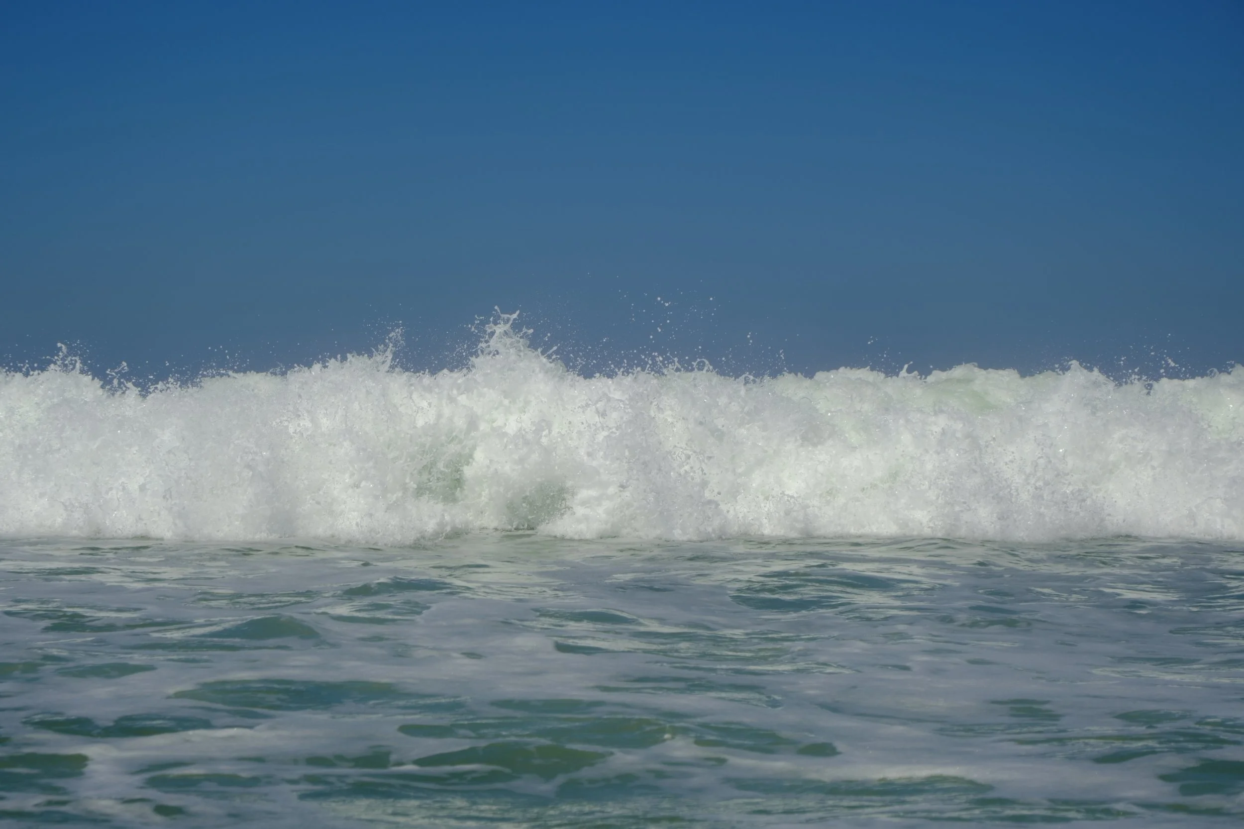 Ocean waves crashing under a clear blue sky