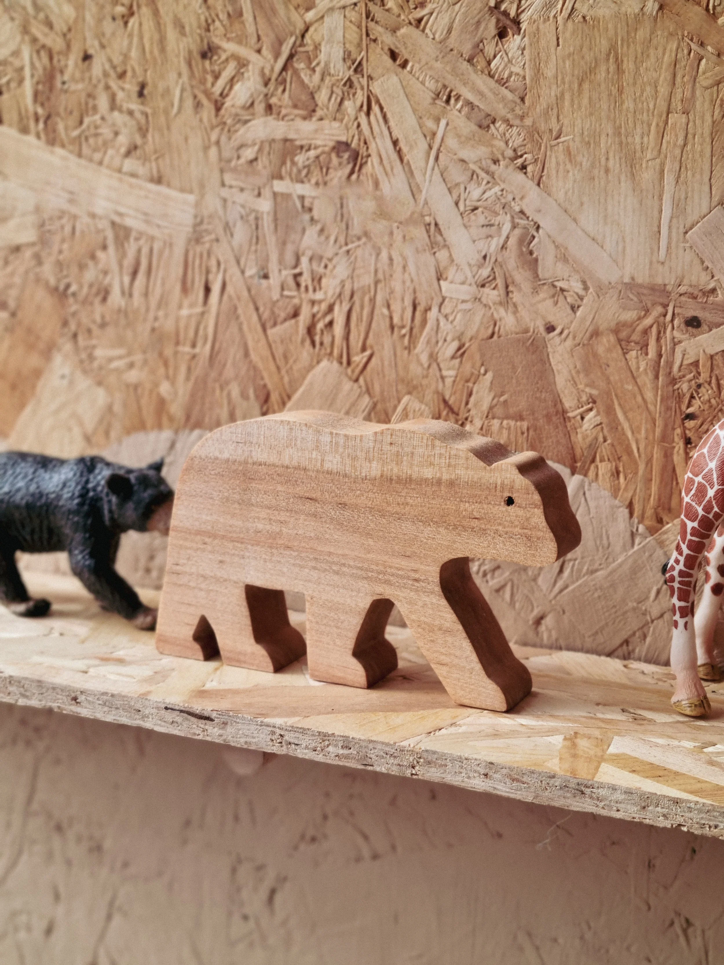 Handmade wooden freestanding bear decoration standing on a wooden shelf.