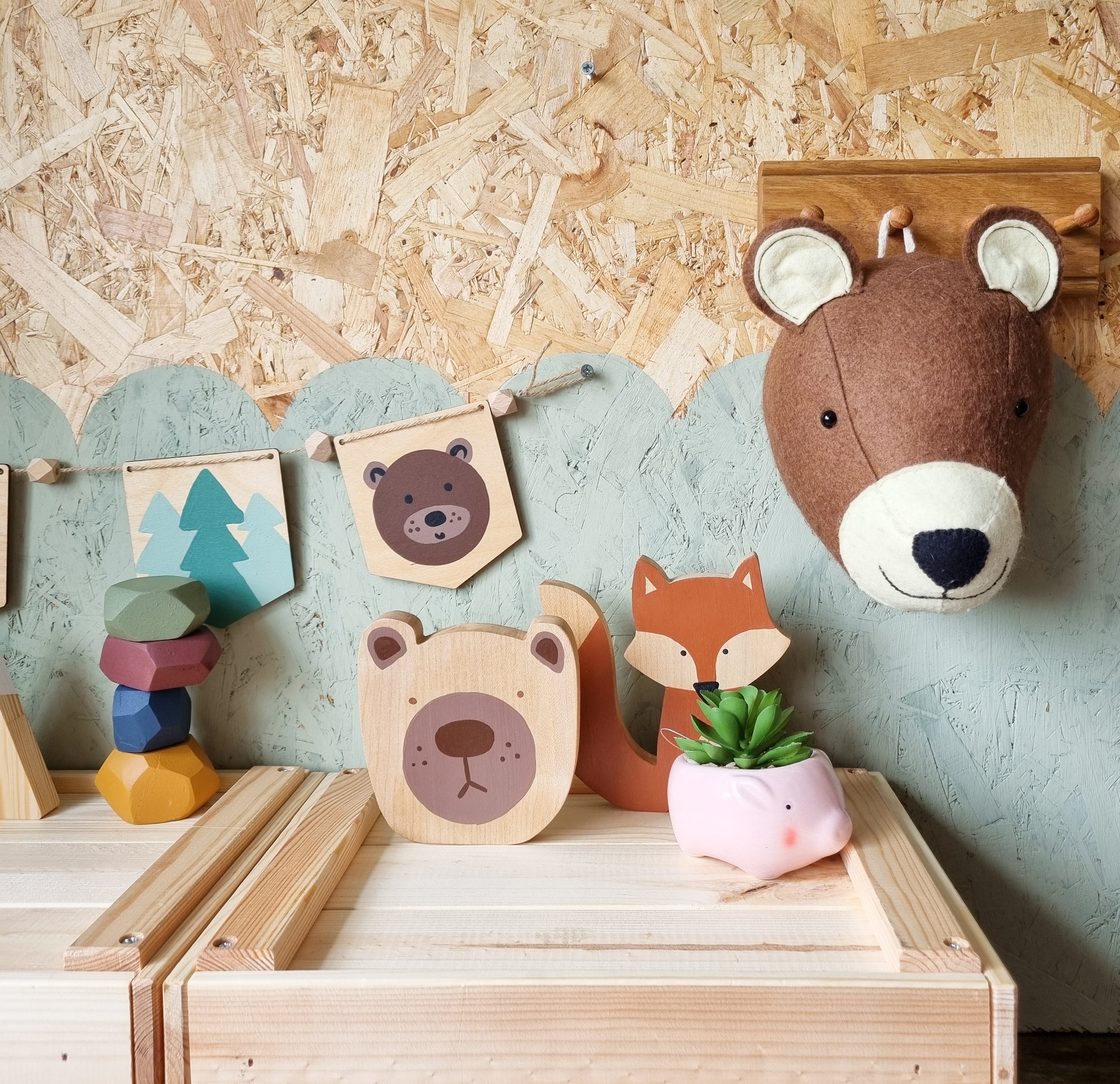 Hand painted wooden bear head decoration in front of a colourful children's decor themed wall.