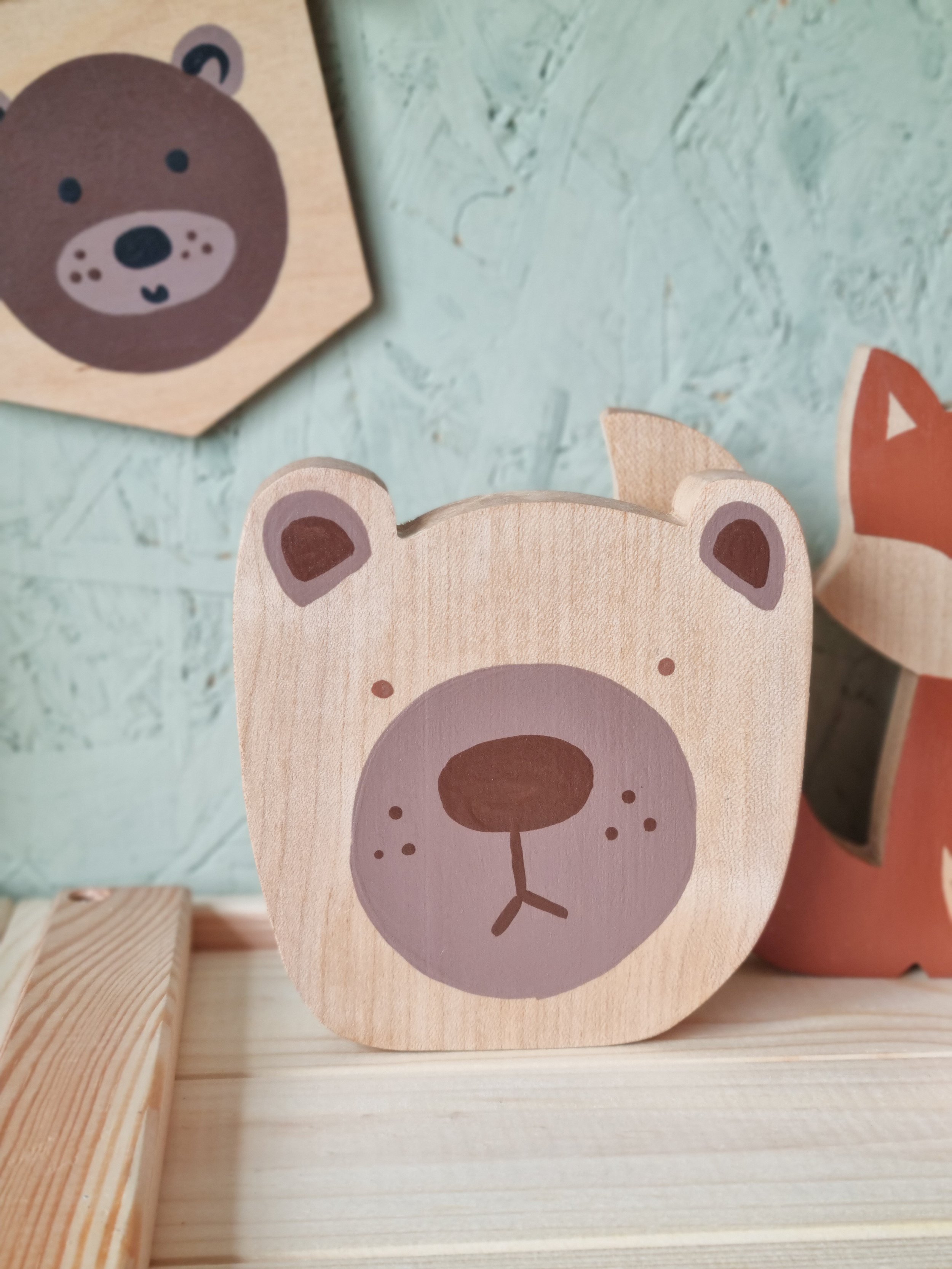 A close up photo of a hand painted wooden bear head ornament.