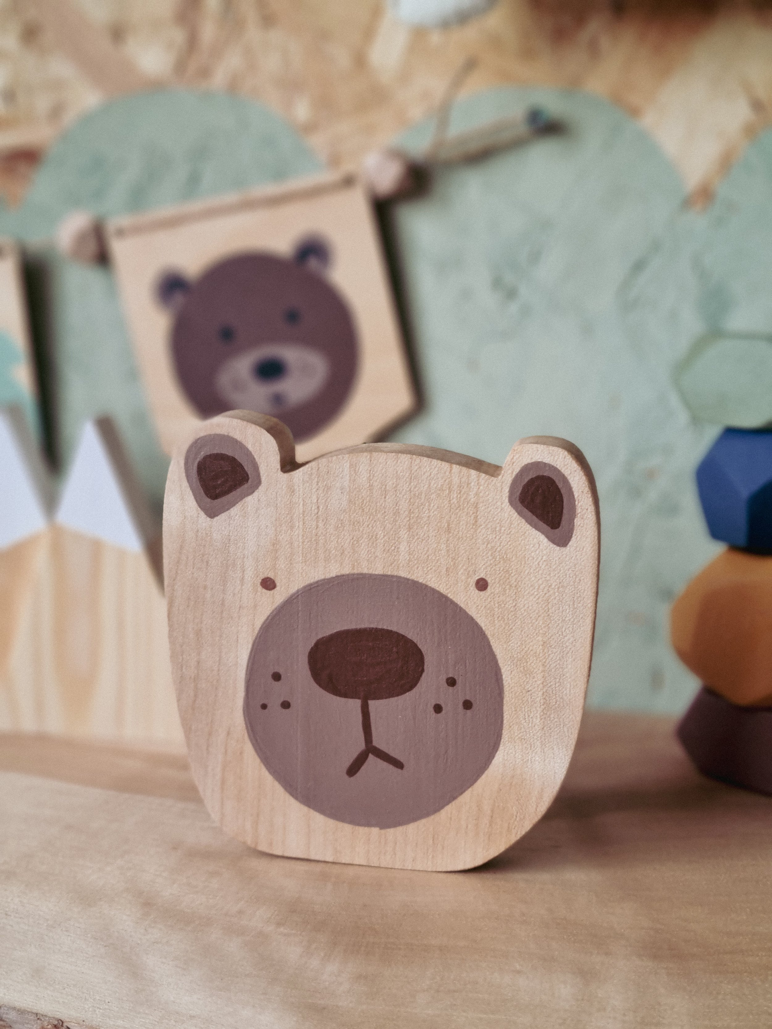 Hand painted wooden bear ornament on display next to some colourful hand painted wooden building blocks